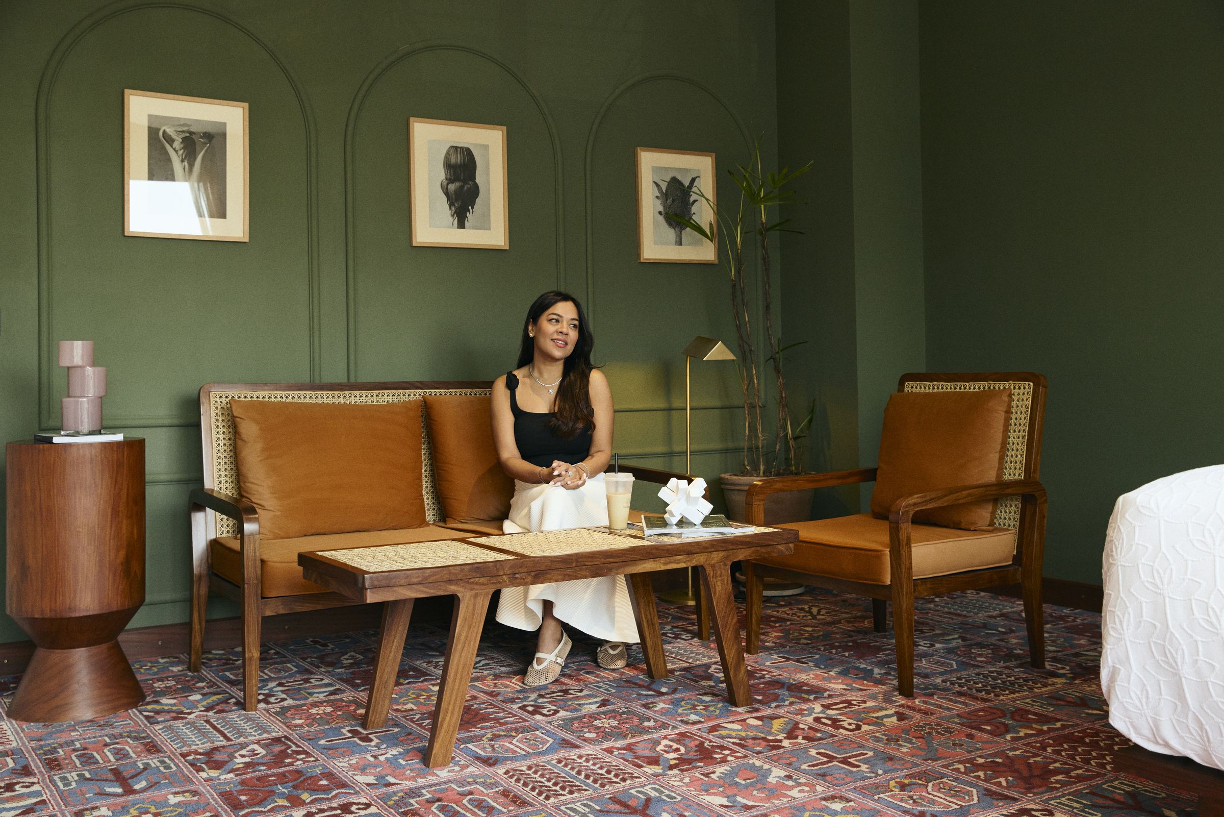 Aleena seated in a warm, sage-green styled living room