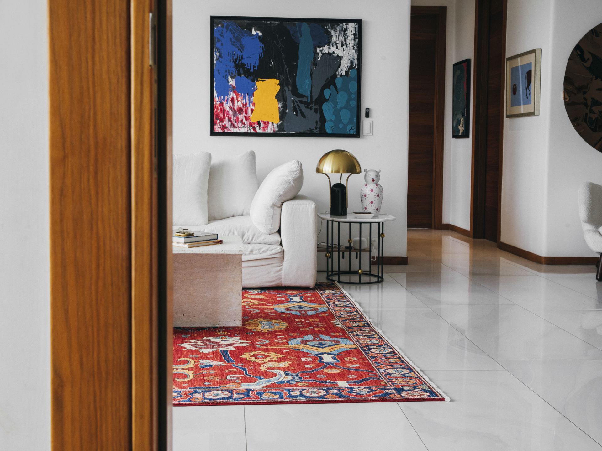 Red medallion Persian rug beneath a white bouclé sofa and abstract painting