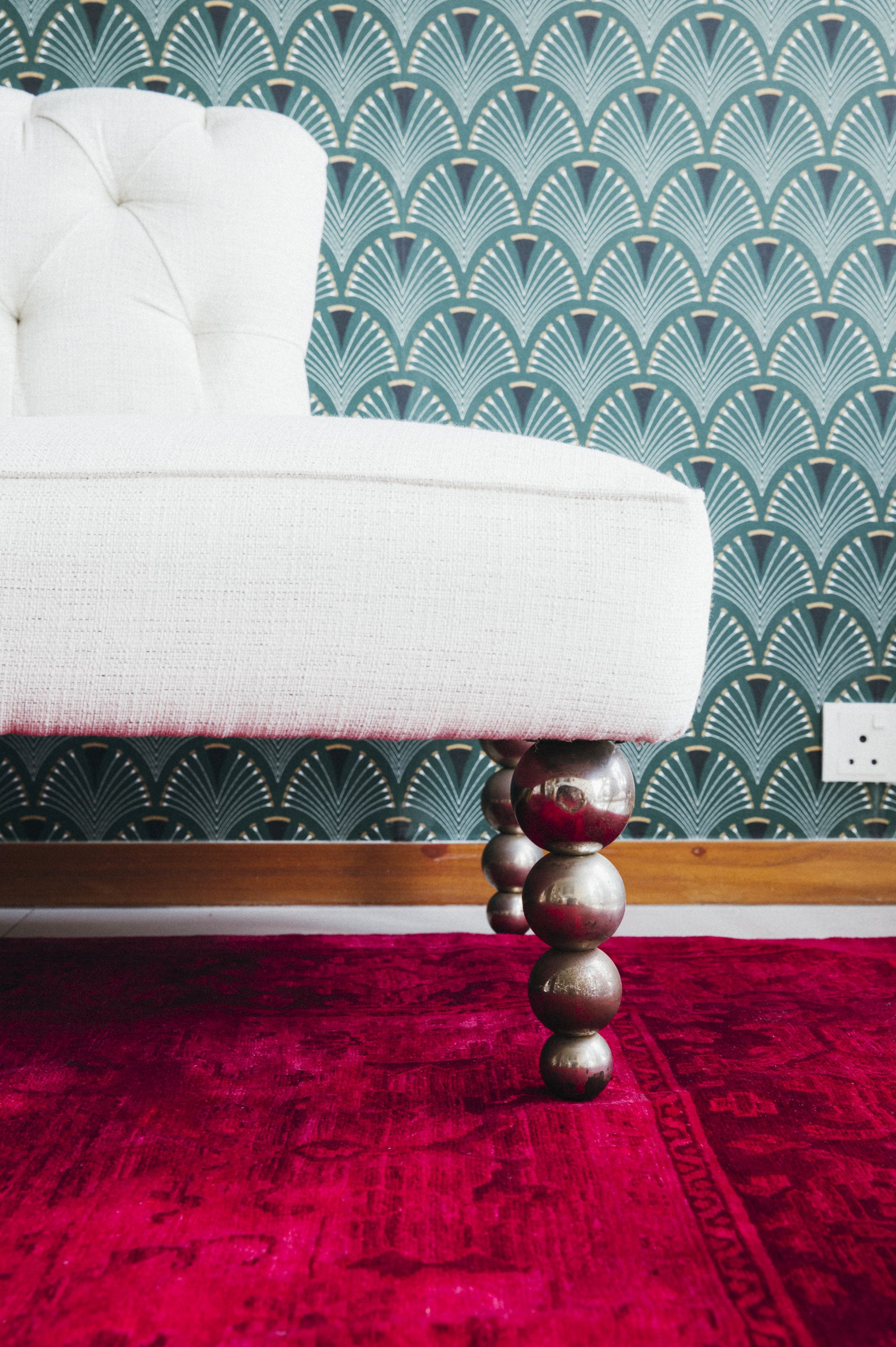 Detail of a tufted chaise's silvered ball feet on a burgundy Persian rug