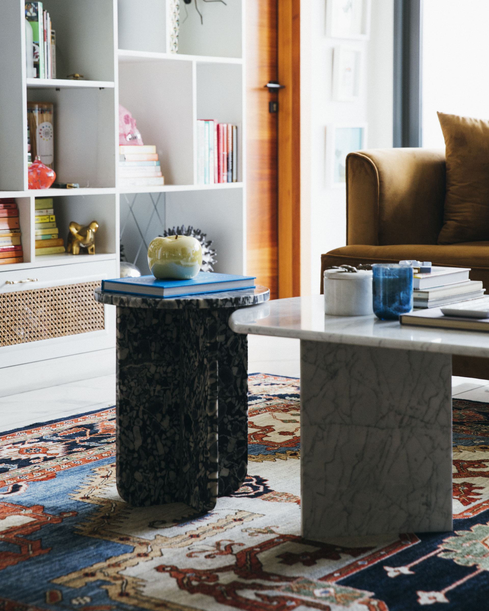 Black marble side table and a white marble coffee table on a red medallion Persian rug