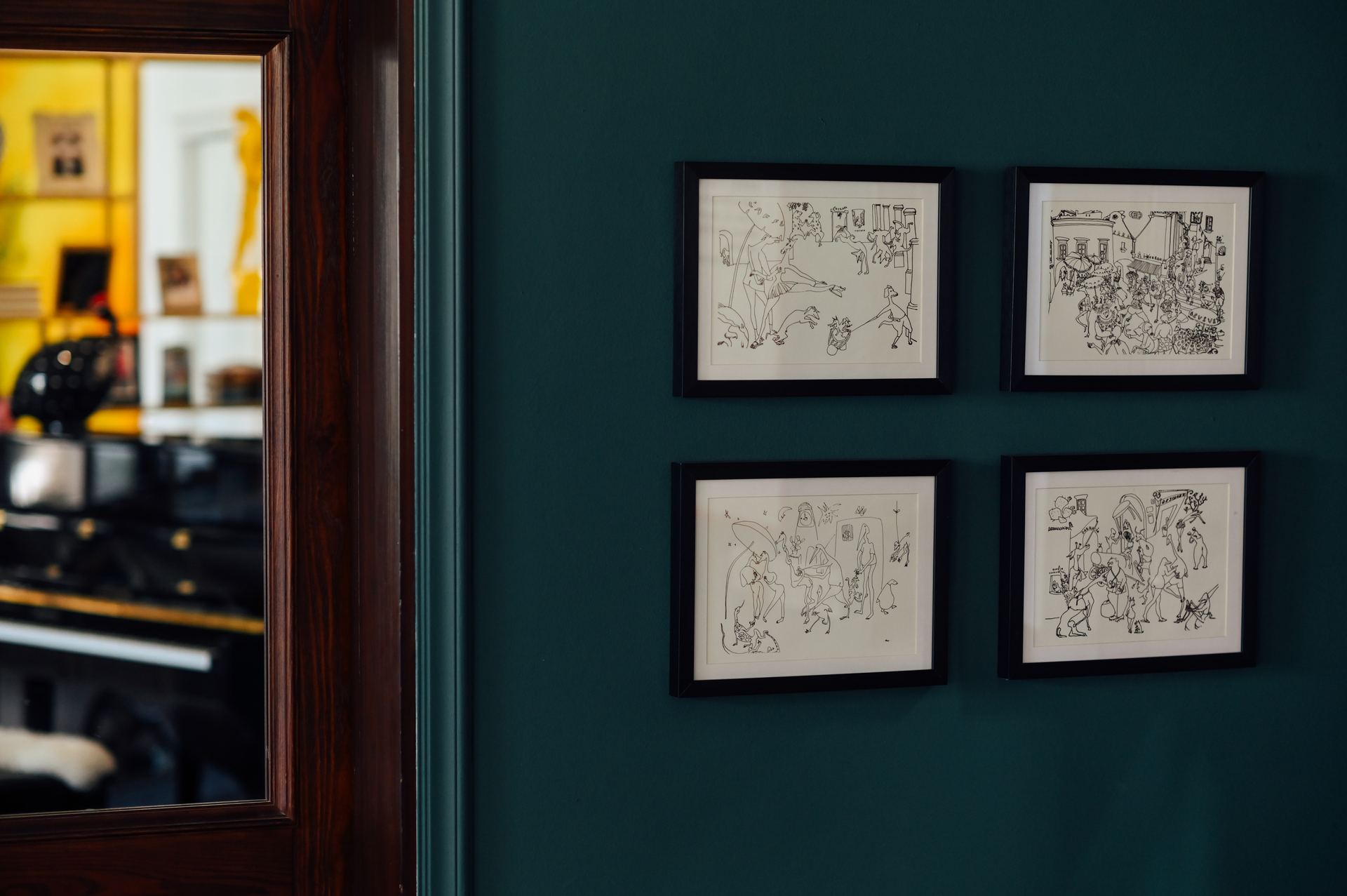 Framed black-and-white illustrated prints on a teal wall
