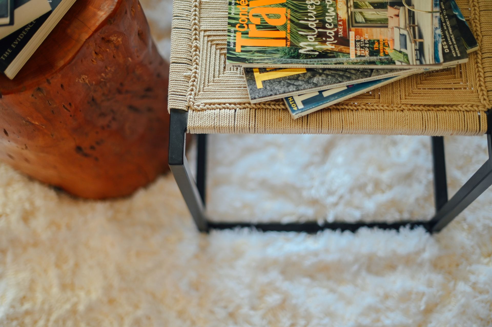 Stack of travel magazines on a woven rattan side table