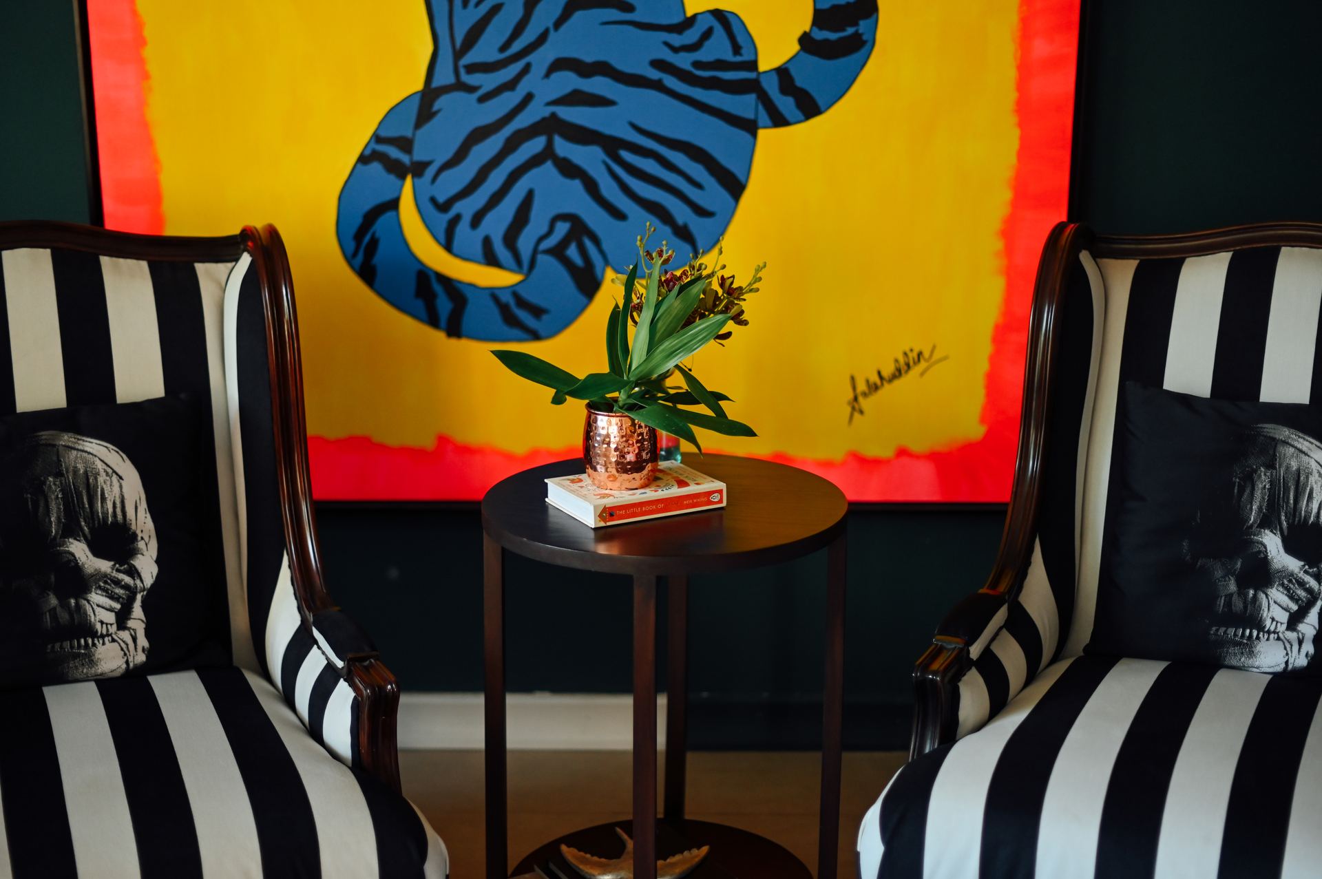 Striped wingback chairs with skull-print cushions flank a round side table