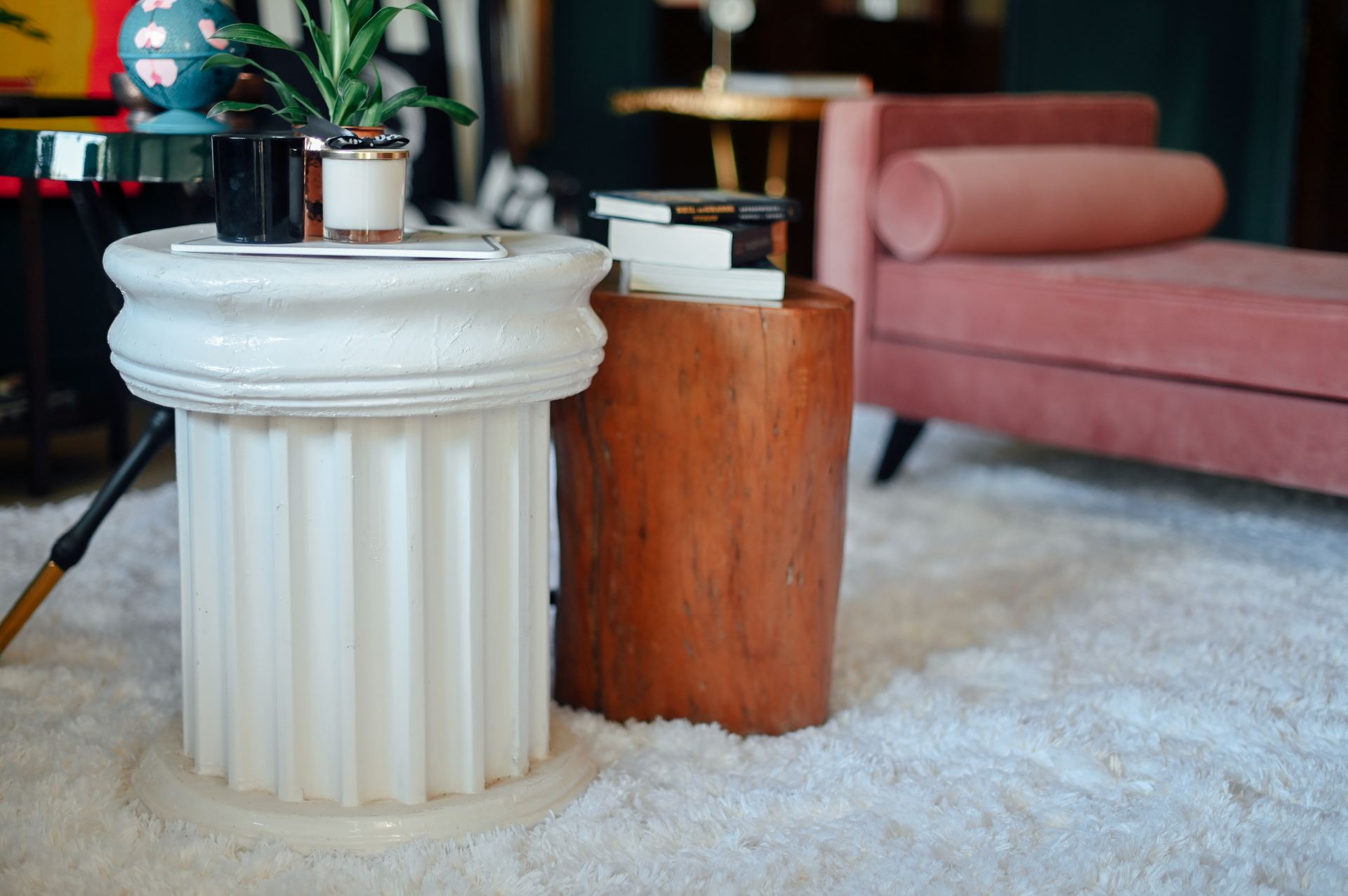 Fluted plaster pedestal and tree-stump side table styled with books