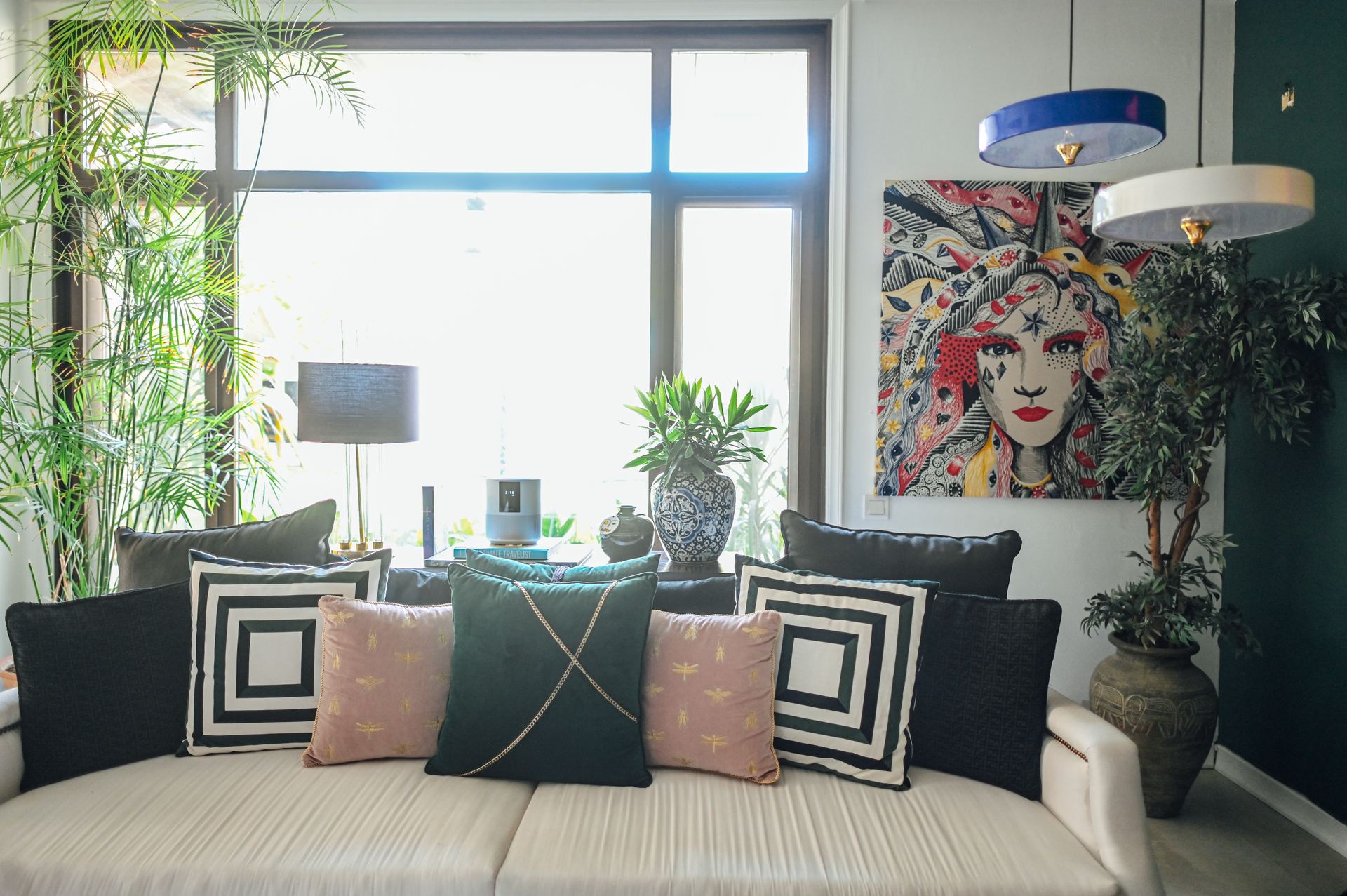 Cream sofa styled with mixed pillows beneath a colorful portrait painting