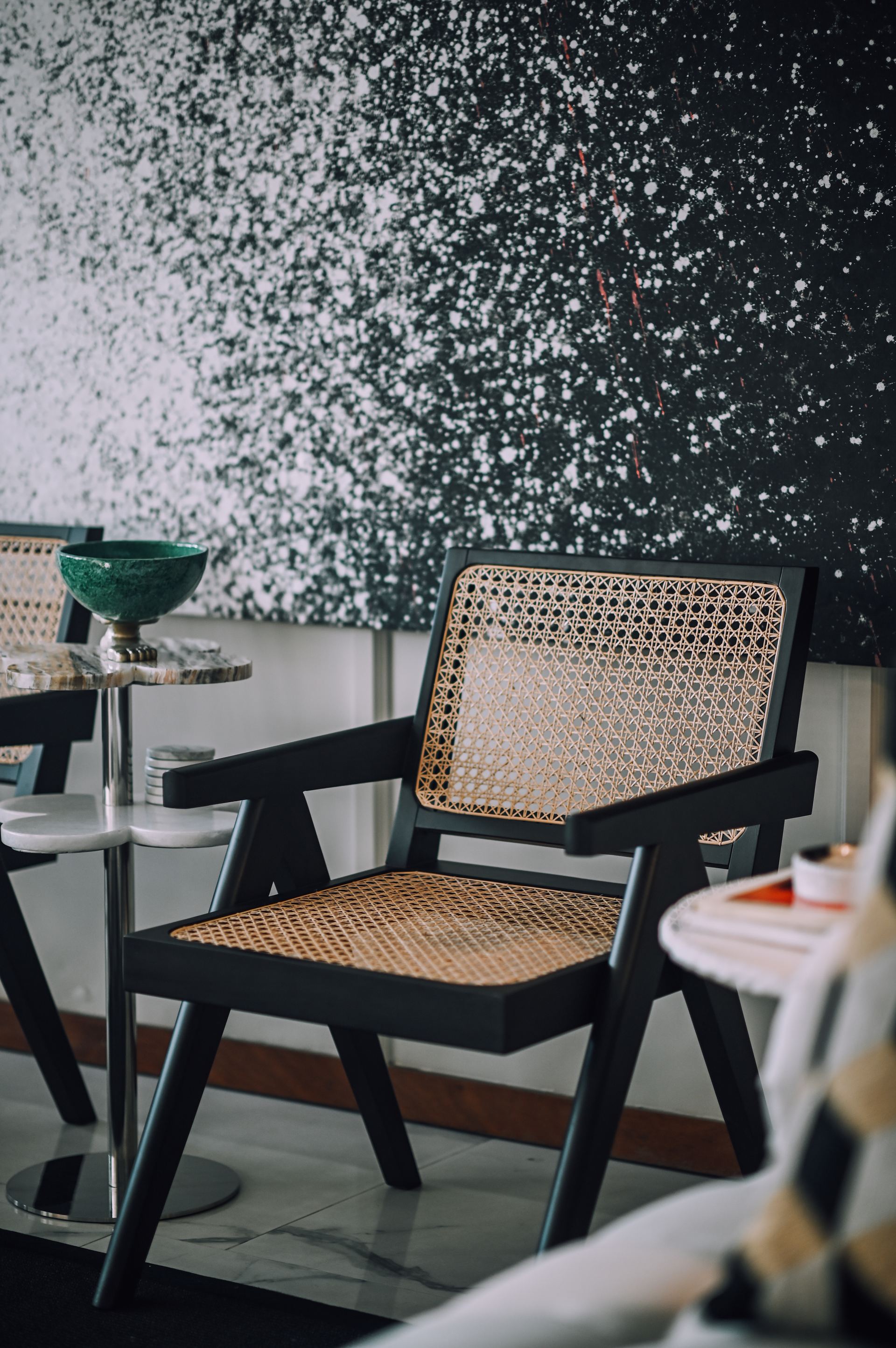 Cane-back armchair beside a speckled black accent wall