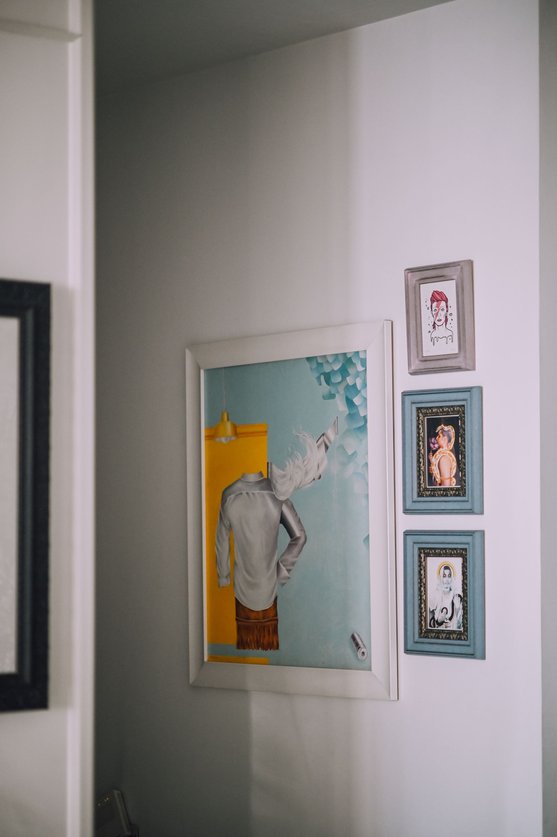 Framed illustrated artworks grouped in a hallway corner