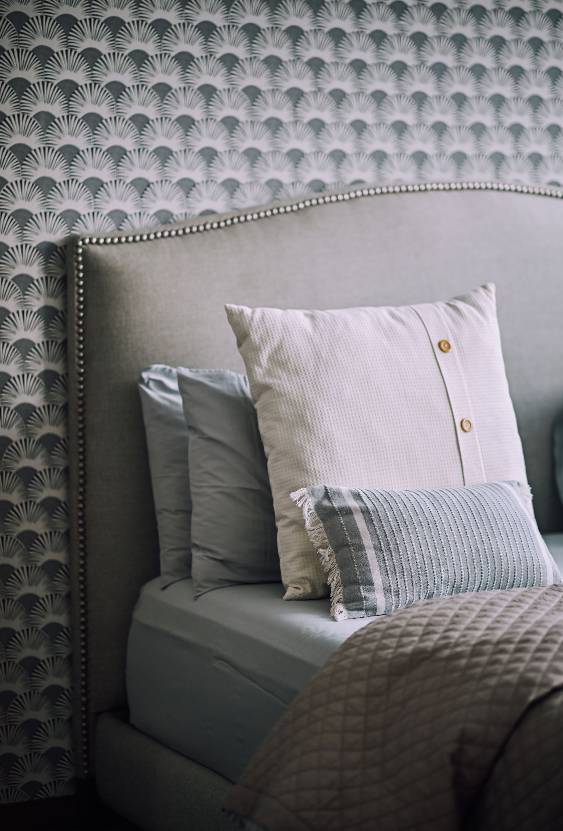 Patterned scallop-print headboard with layered pillows and a quilted throw