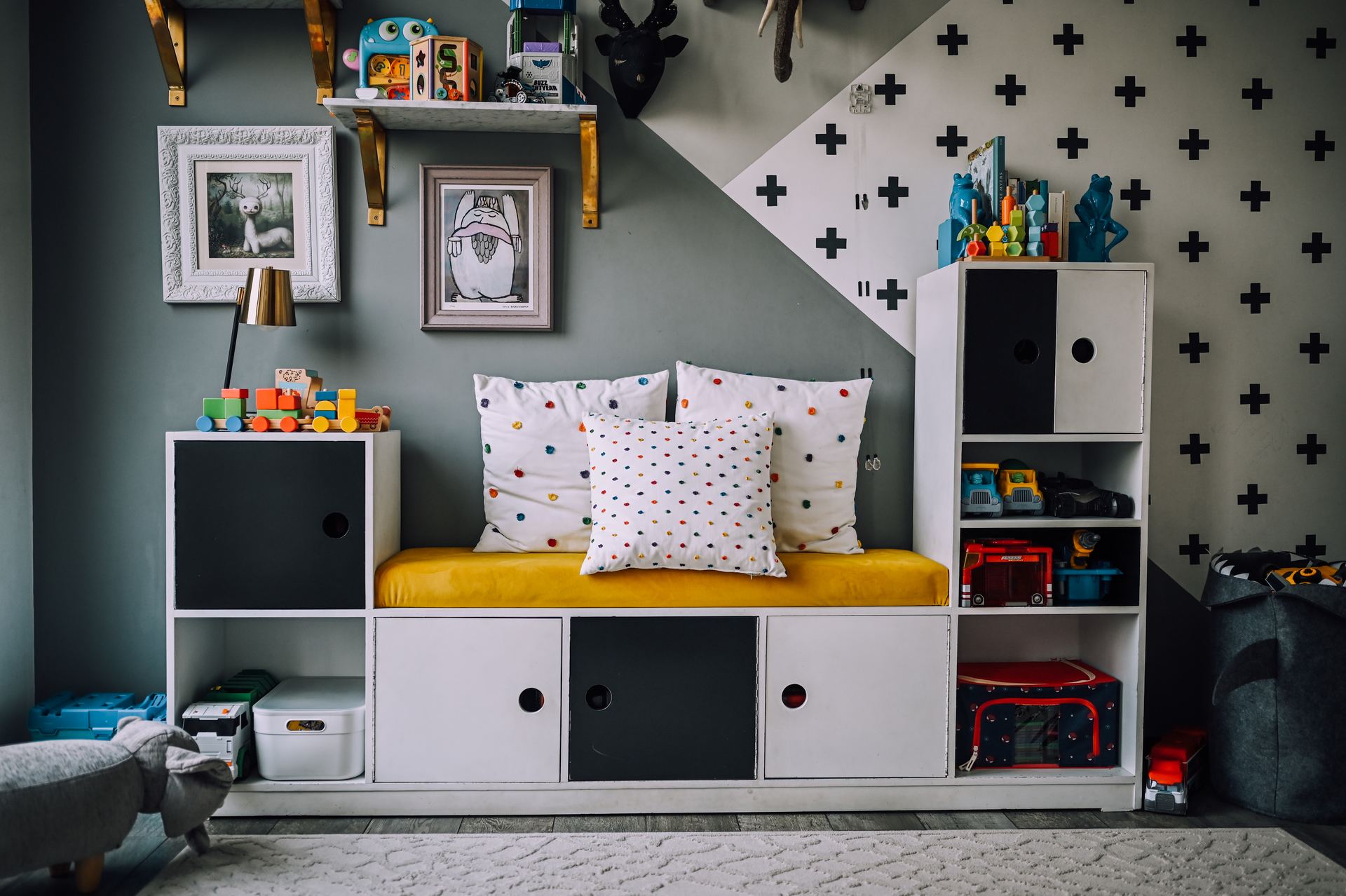 Kids playroom nook with a mustard storage bench and geometric wallpaper