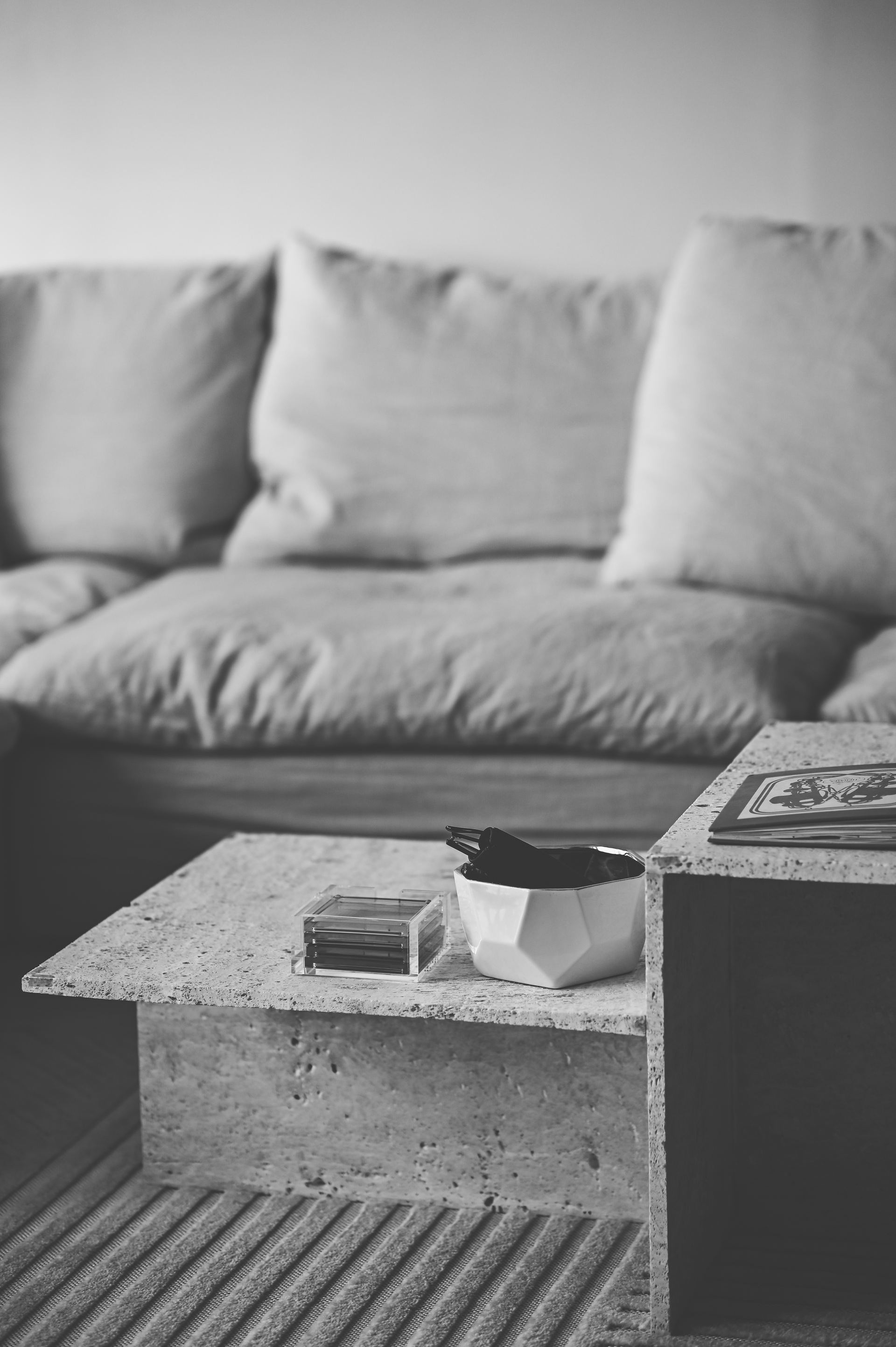 Black-and-white detail of a concrete coffee table beside a linen sofa