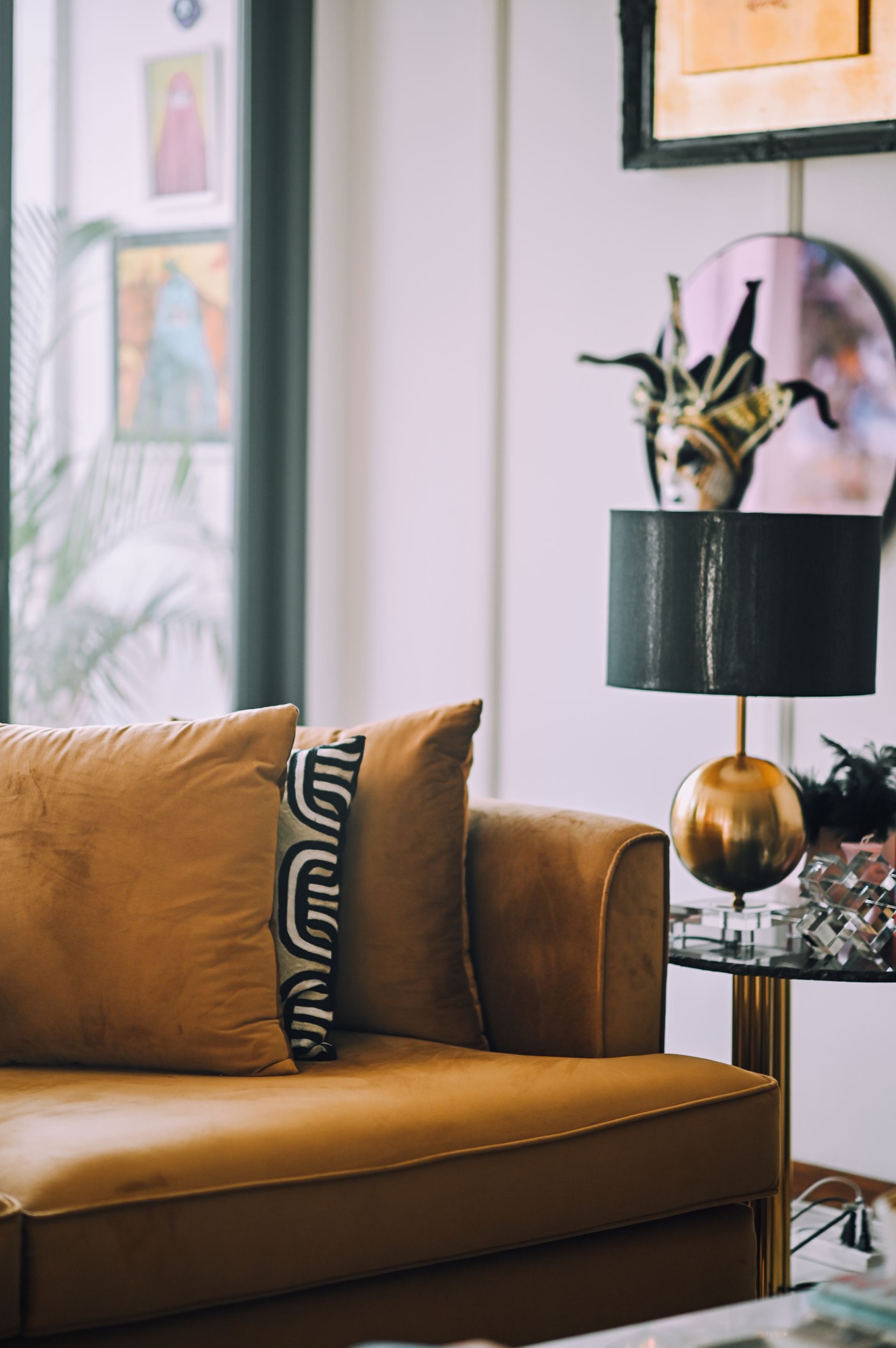 Mustard velvet sofa with a graphic cushion beside a brass table lamp