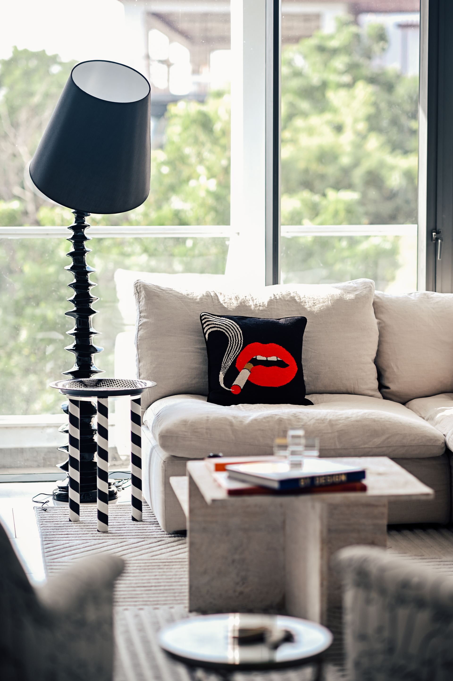 Ribbed black floor lamp beside a cream sofa with a smoking-lips cushion