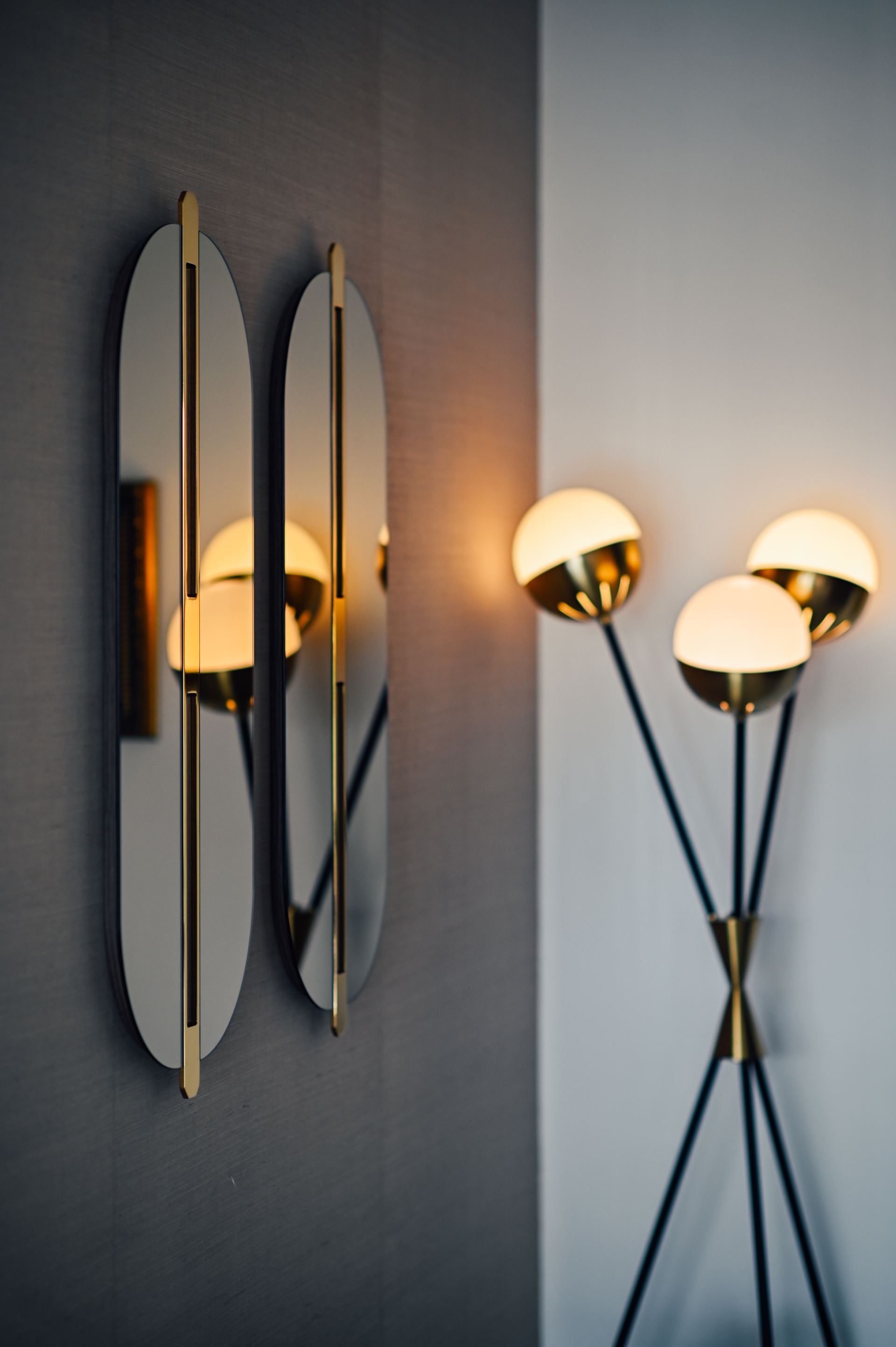 Pair of oval brass-trimmed wall sconces beside a gold globe floor lamp