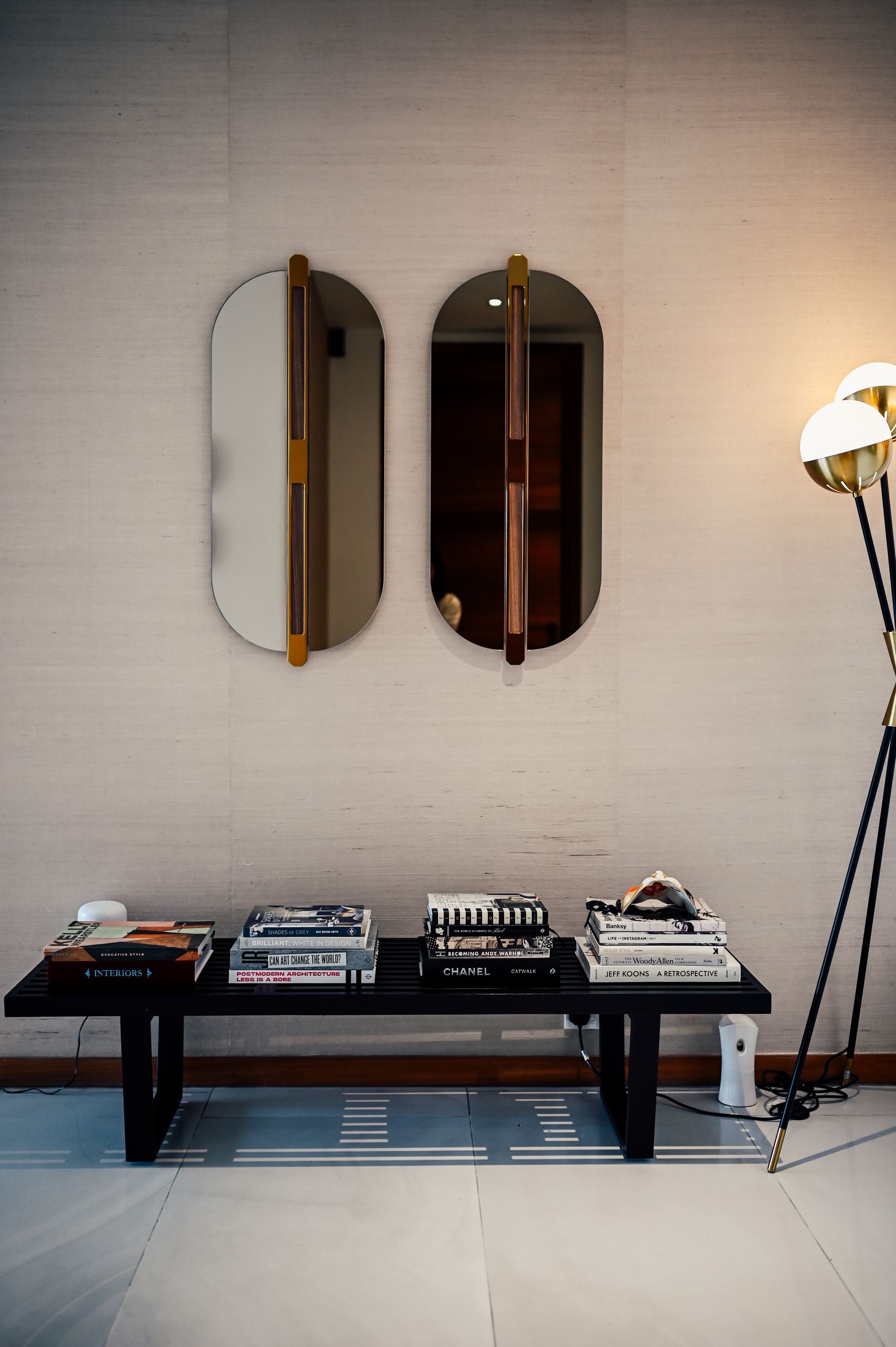 Pair of oval mirrors with wooden handles above a bench of stacked books