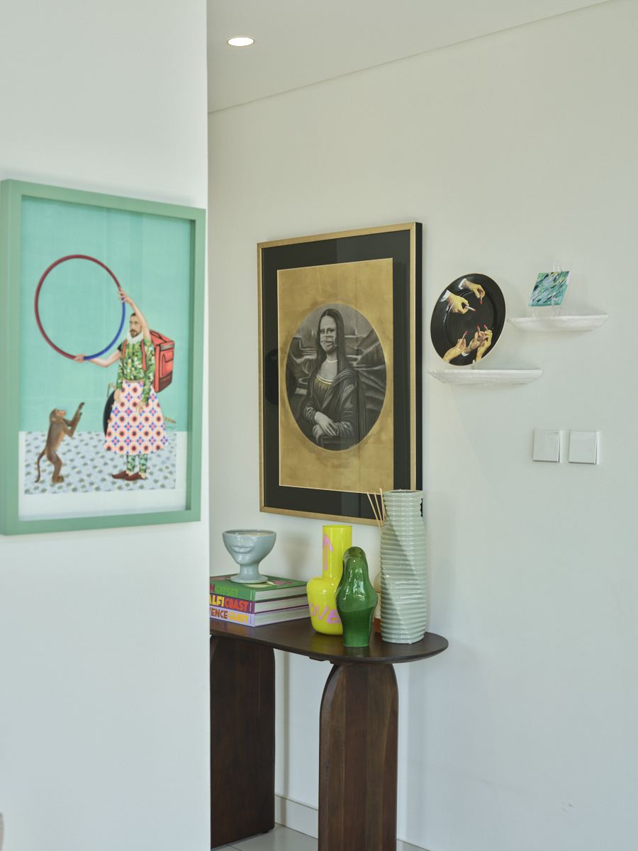 Whimsical illustrated wall art beside a curved console styled with ceramic vases