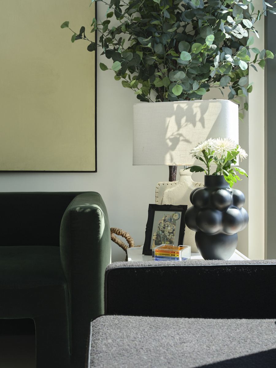 Charcoal leather armchair beside a sculptural black vase and table lamp