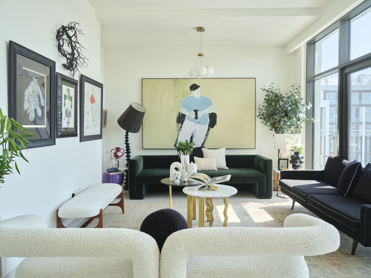 Living room with a green velvet sofa, bouclé armchairs, and a large figurative painting