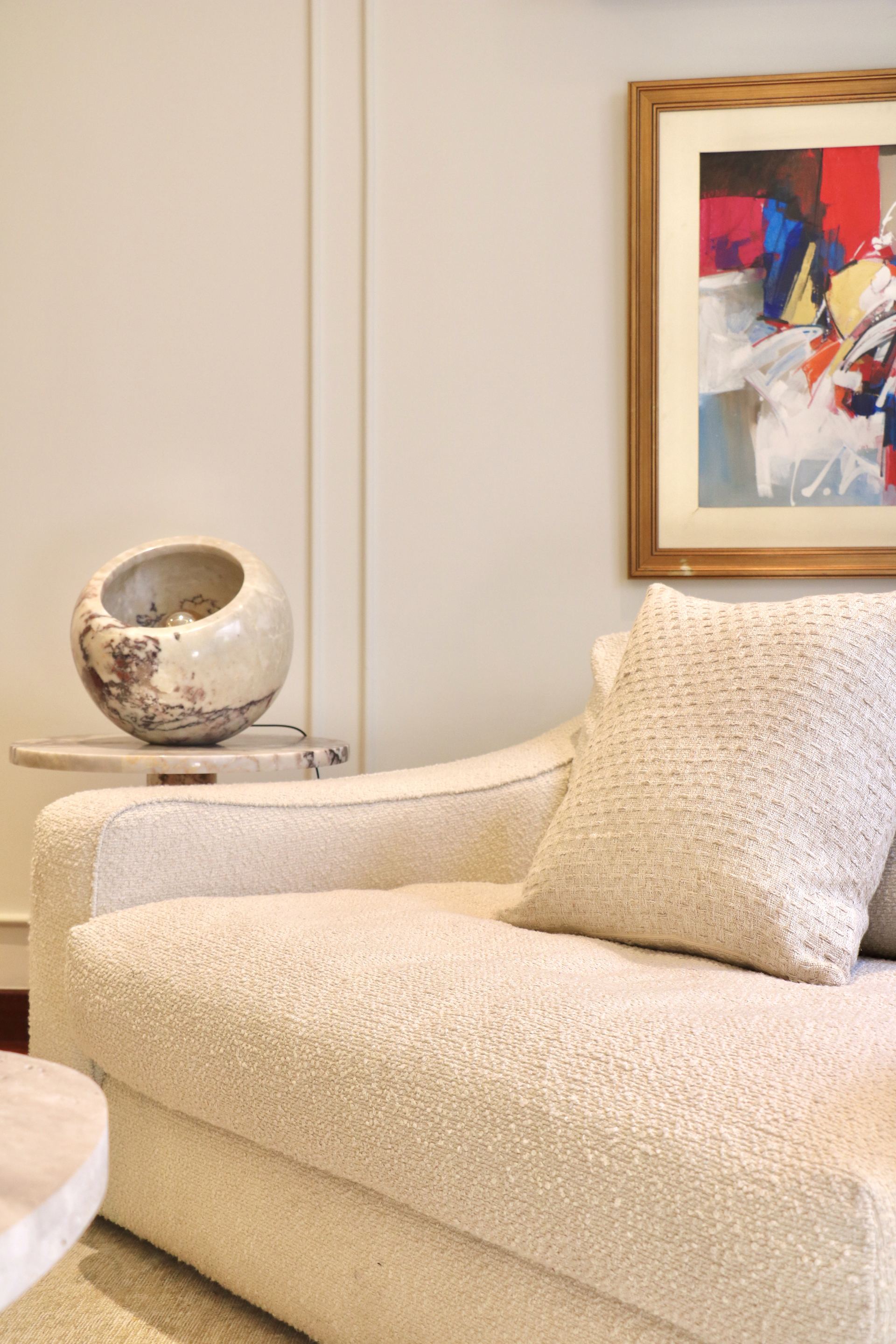 Bouclé armchair with a textured cushion beside a colorful abstract painting