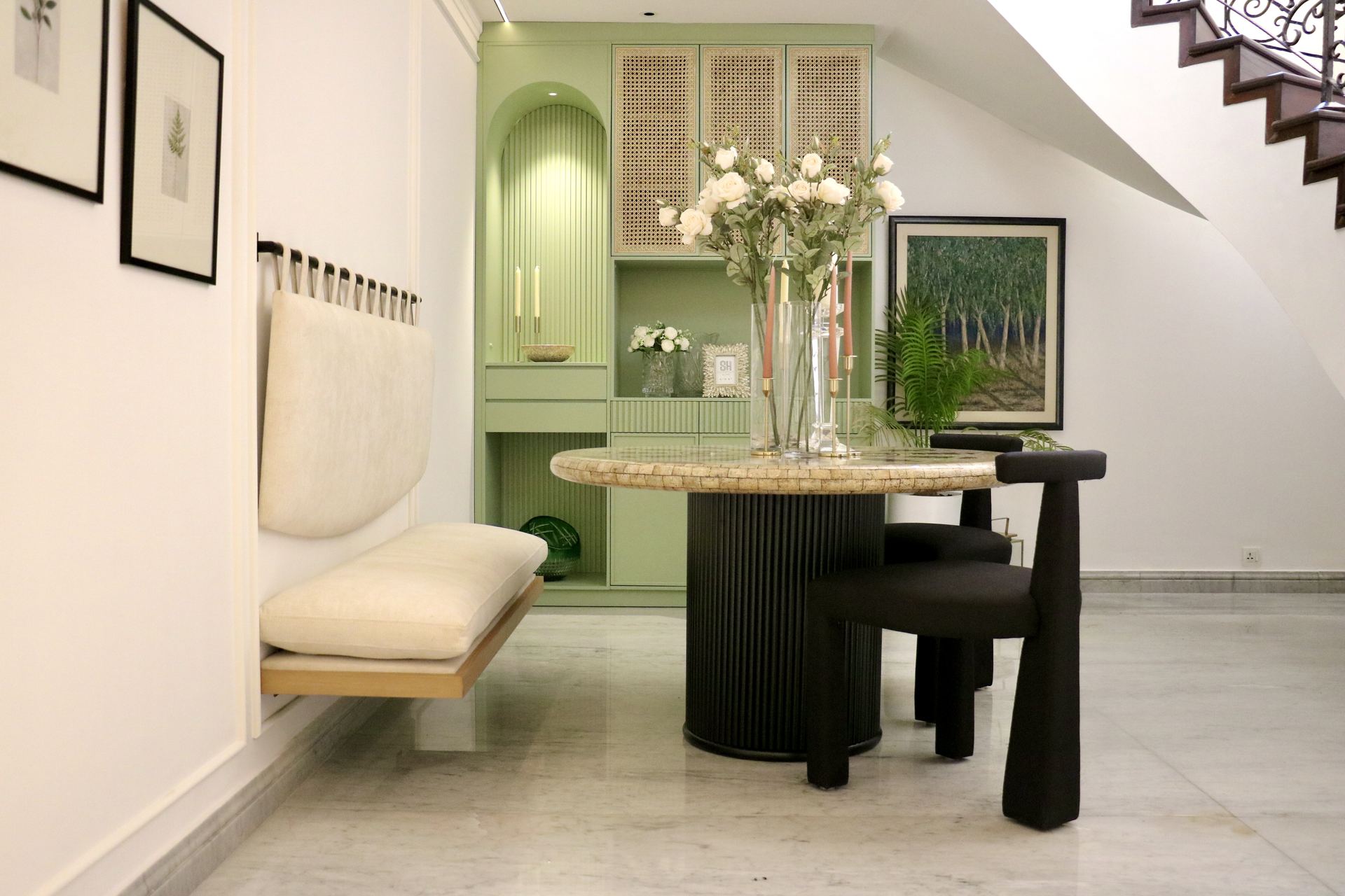 Sage-green built-in cabinetry styled with roses beside a mosaic dining table