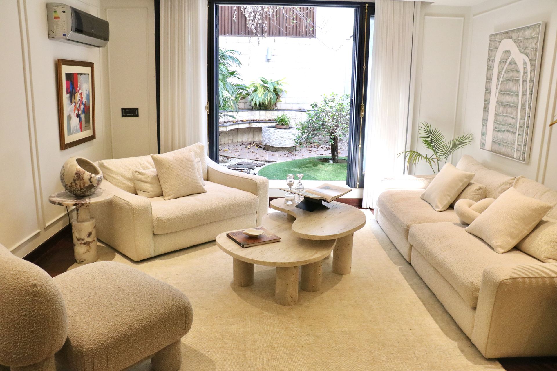 Cream living room opening onto a courtyard through floor-to-ceiling doors