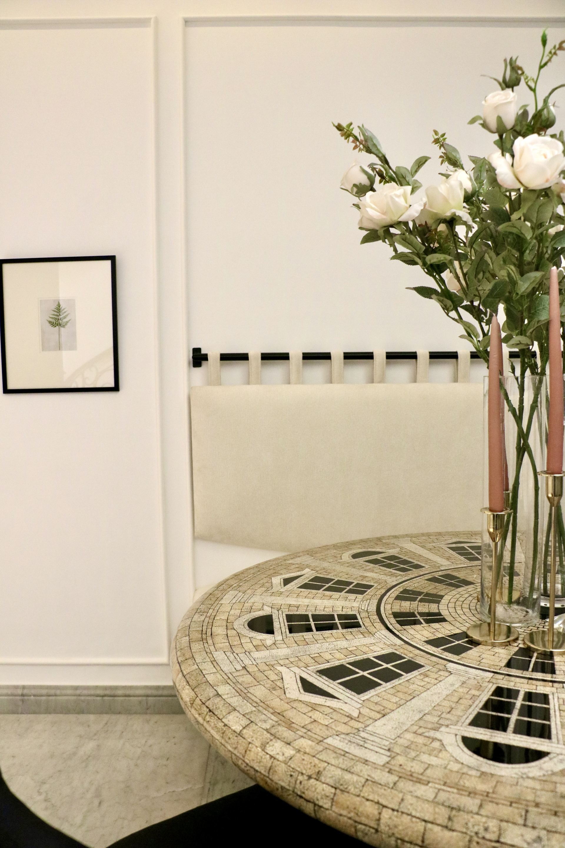 Detail of a mosaic dining table set with pink taper candles and roses