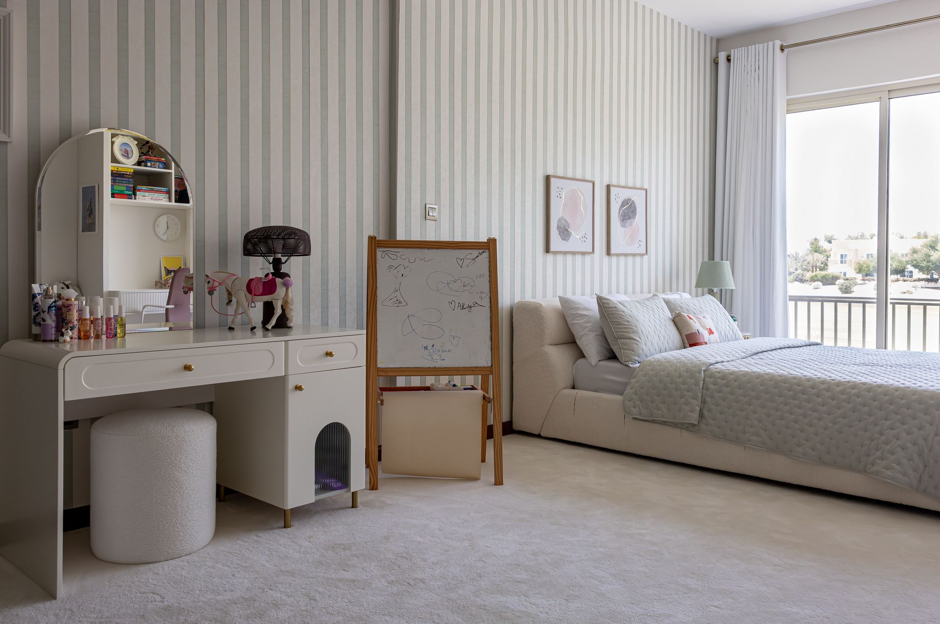 Striped-wallpaper bedroom with a vanity desk, whiteboard easel, and balcony view