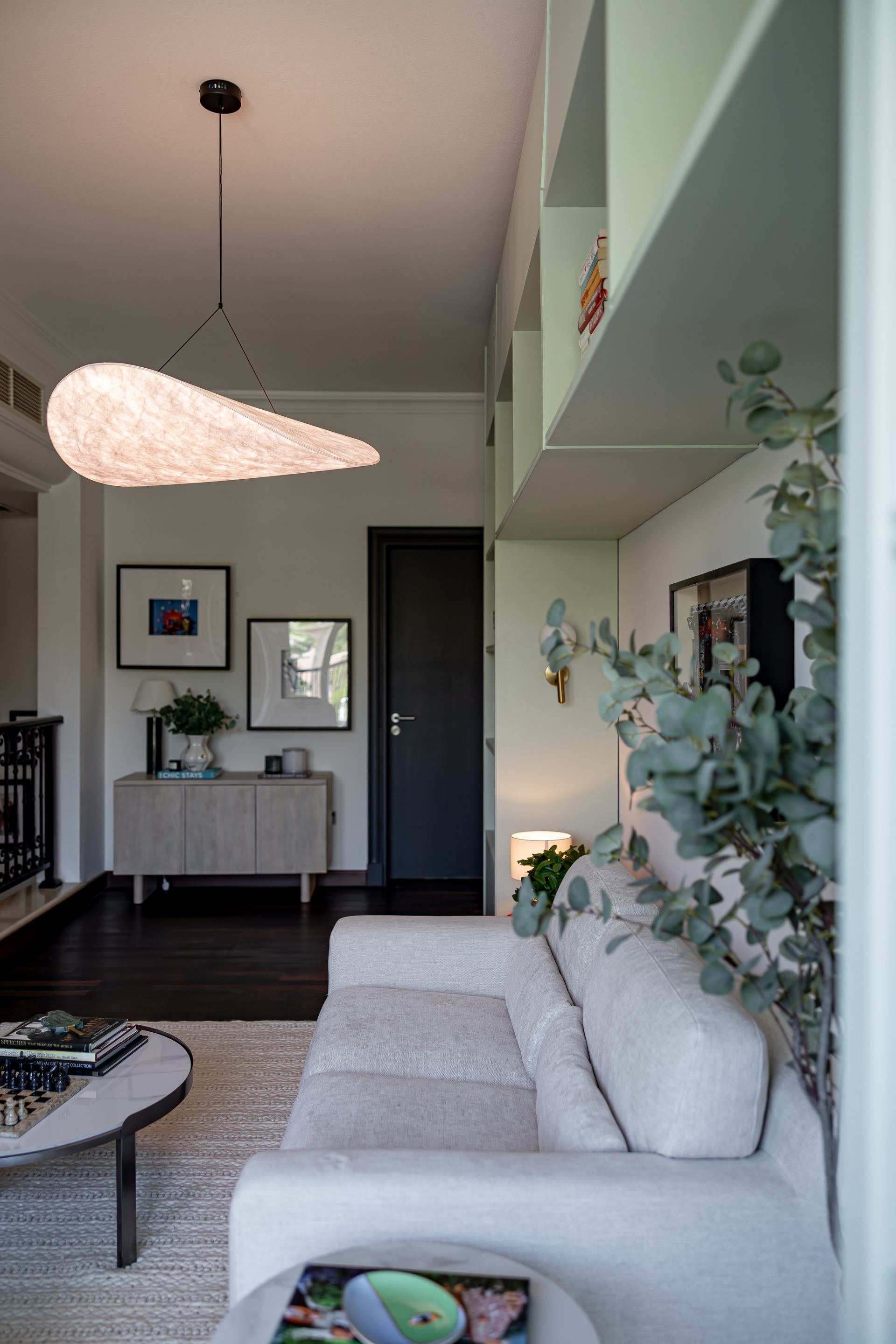 Curved cocoon pendant light above a stairwell console and living room sofa