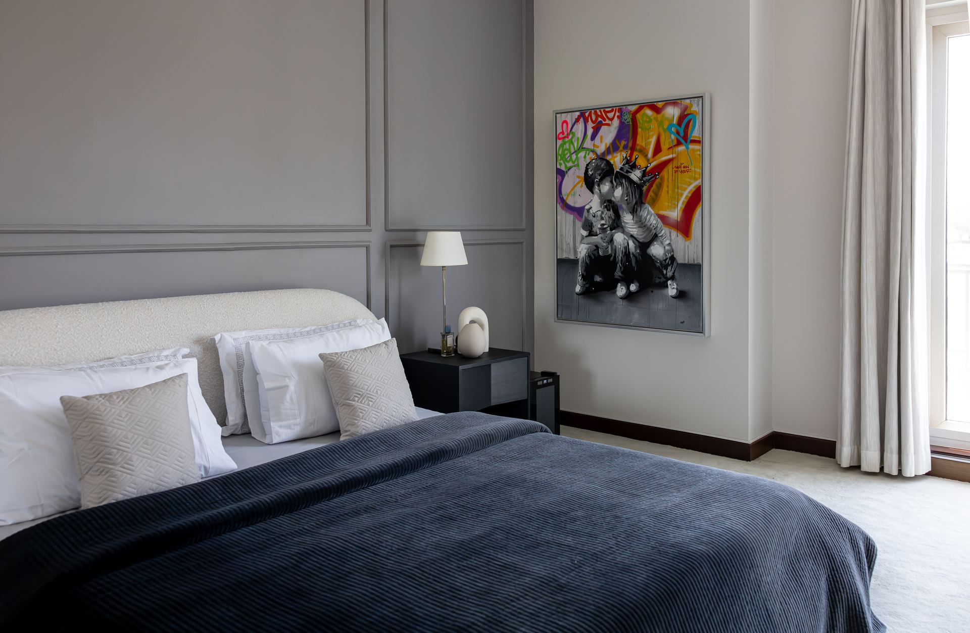 Charcoal-grey bedroom with a graffiti-style portrait painting above a bedside table