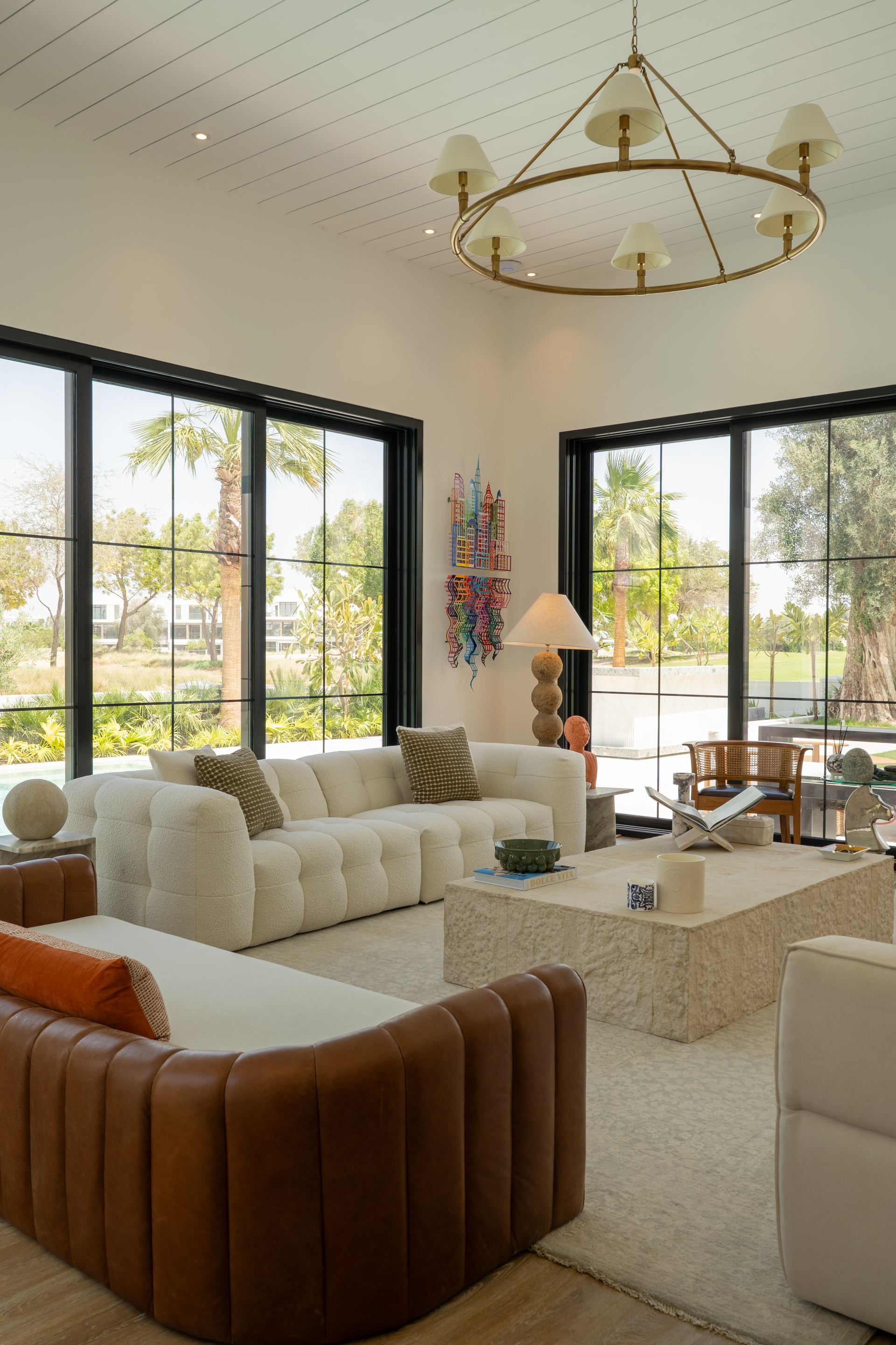 Cane bouclé sofa and a tan leather sofa facing a stone coffee table by the pool