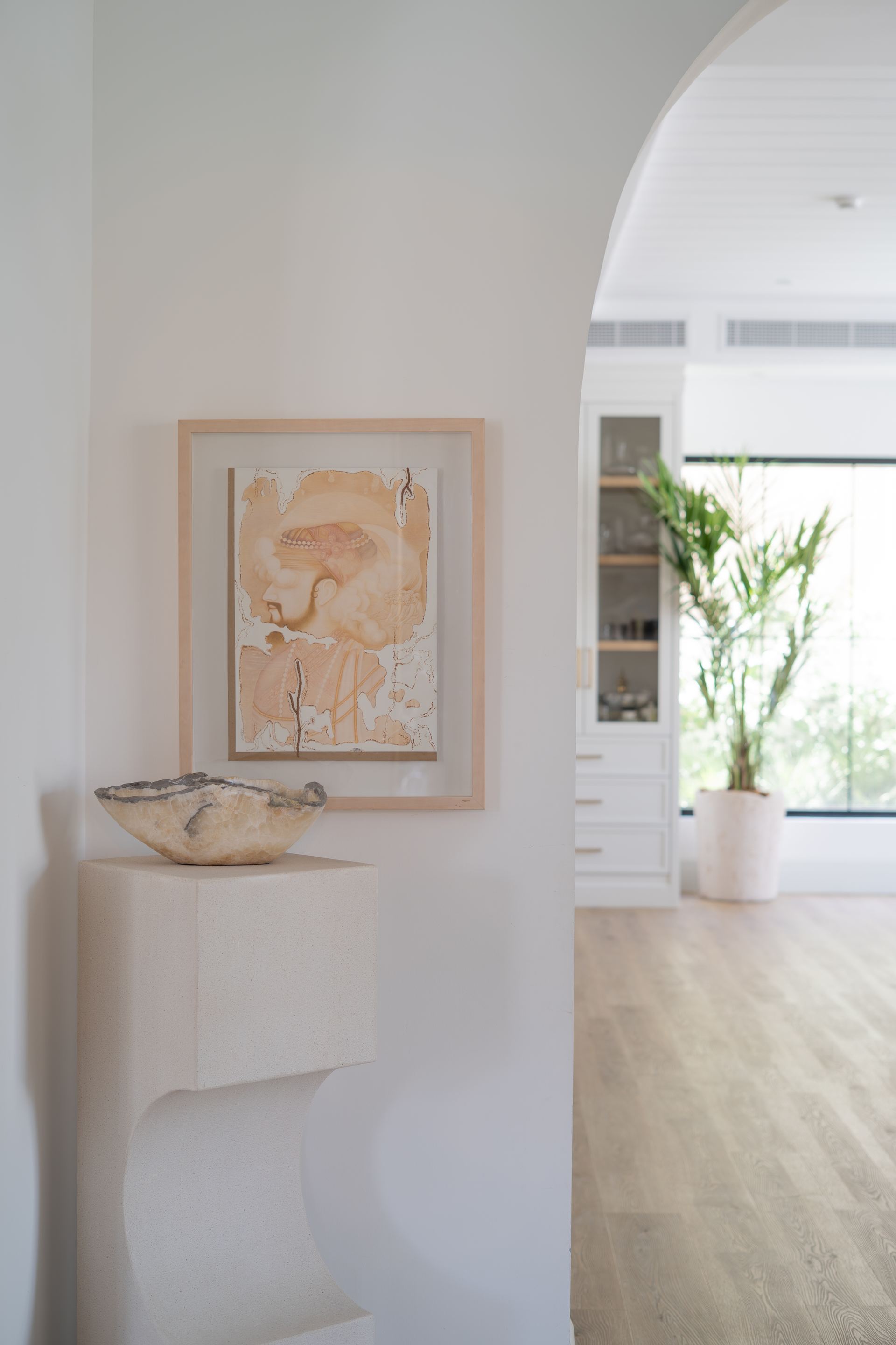 Framed watercolor artwork above a carved travertine pedestal