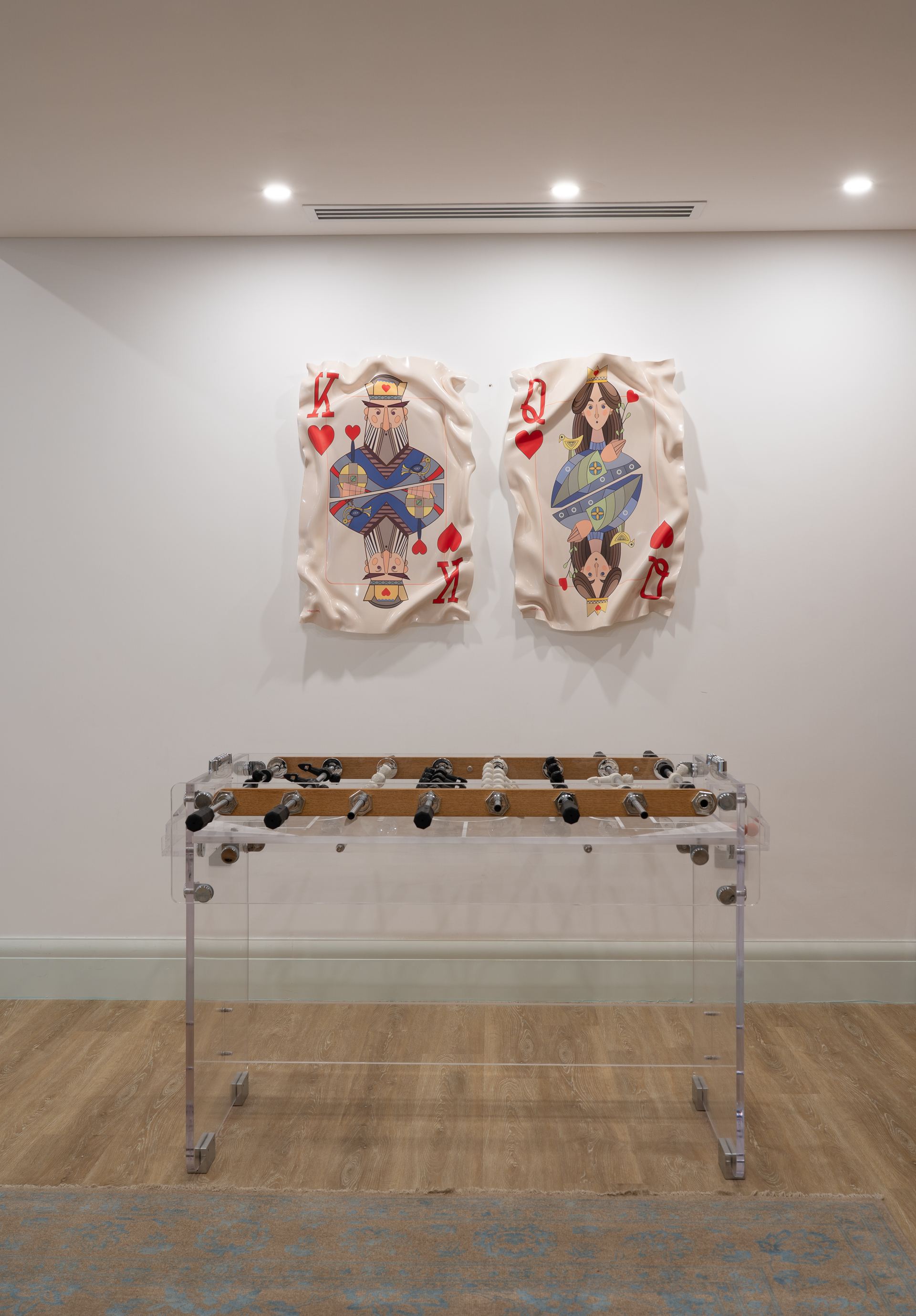 Playful king-and-queen playing-card wall art above an acrylic foosball table