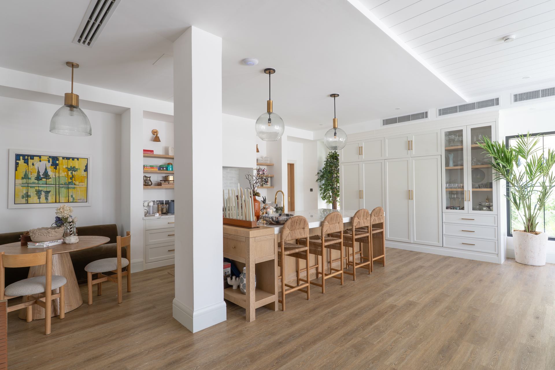 Open kitchen with a wood island, pendant lights, and cane dining chairs