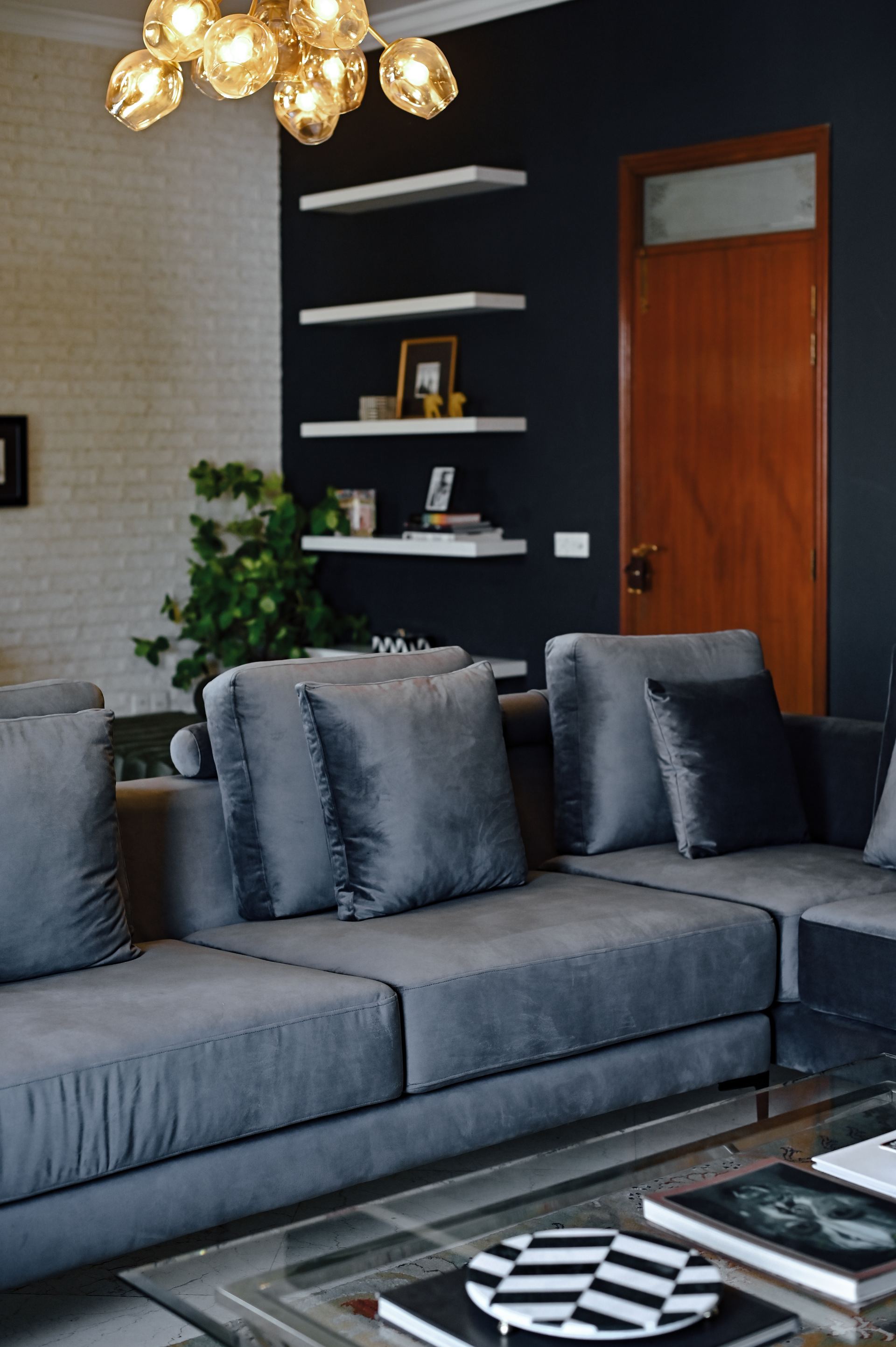 Grey velvet sofa with layered cushions beneath a brass sputnik chandelier