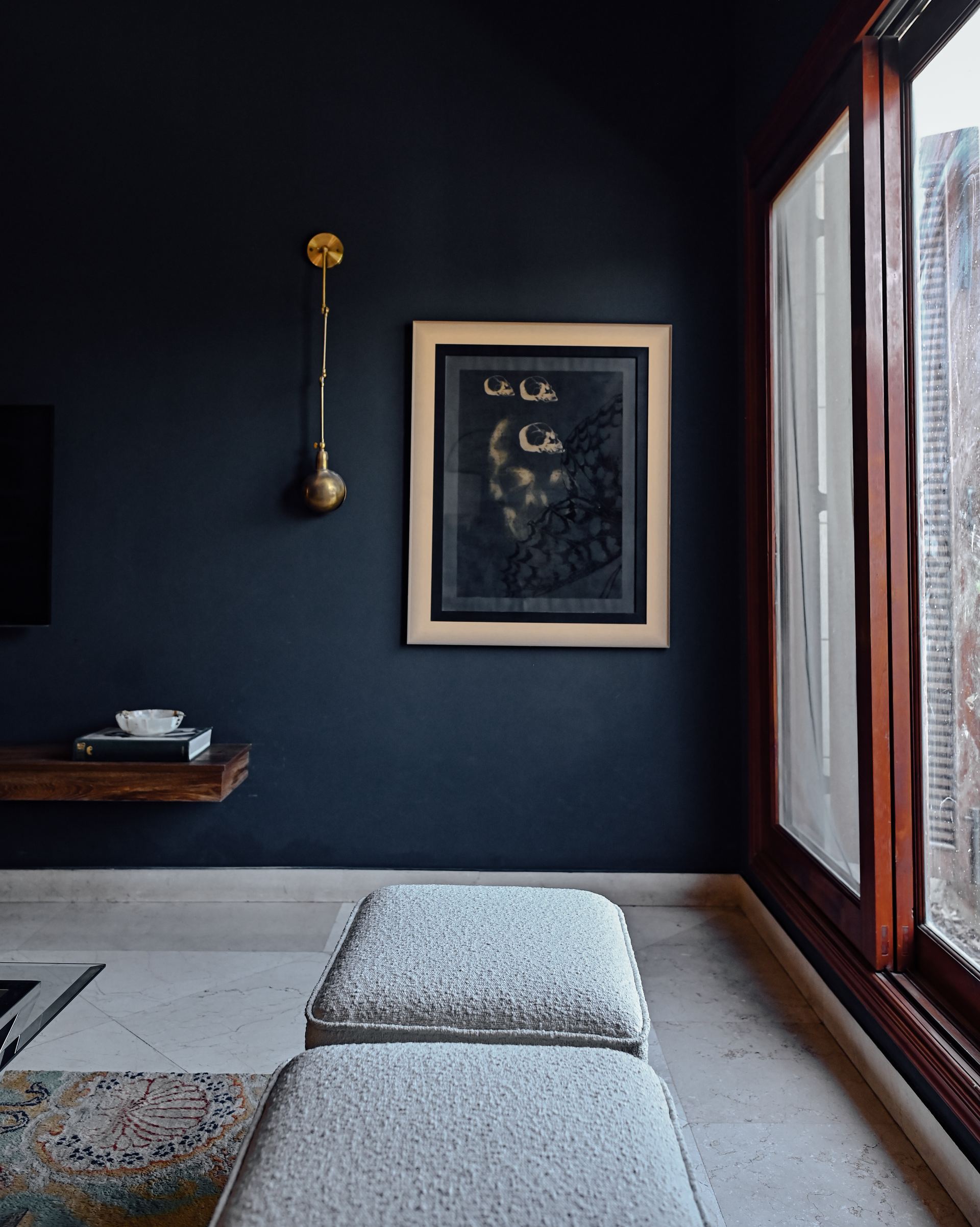 Brass wall sconce beside a framed abstract artwork on a charcoal wall