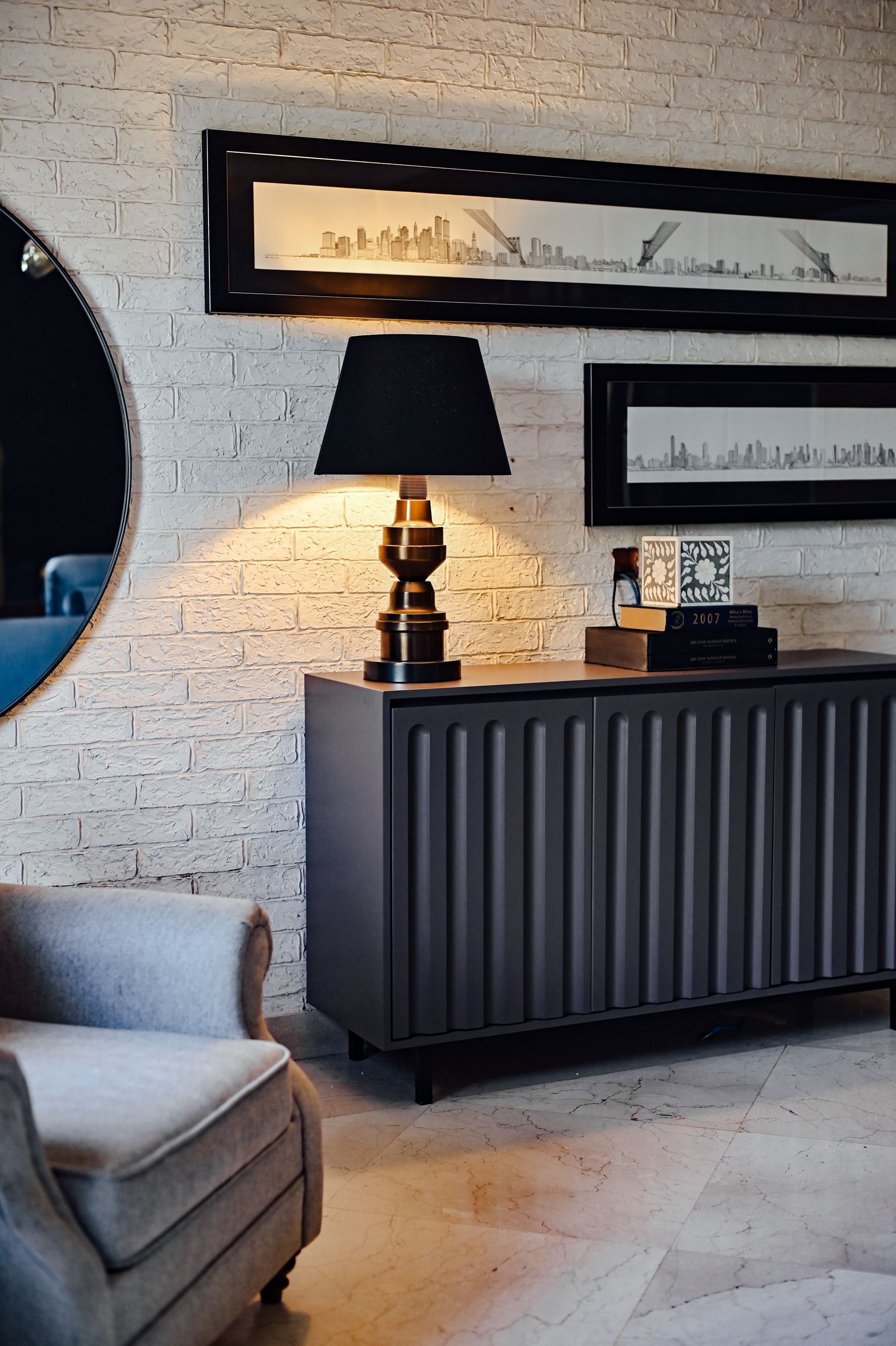 Charcoal brick wall styled with a table lamp and framed city-skyline prints
