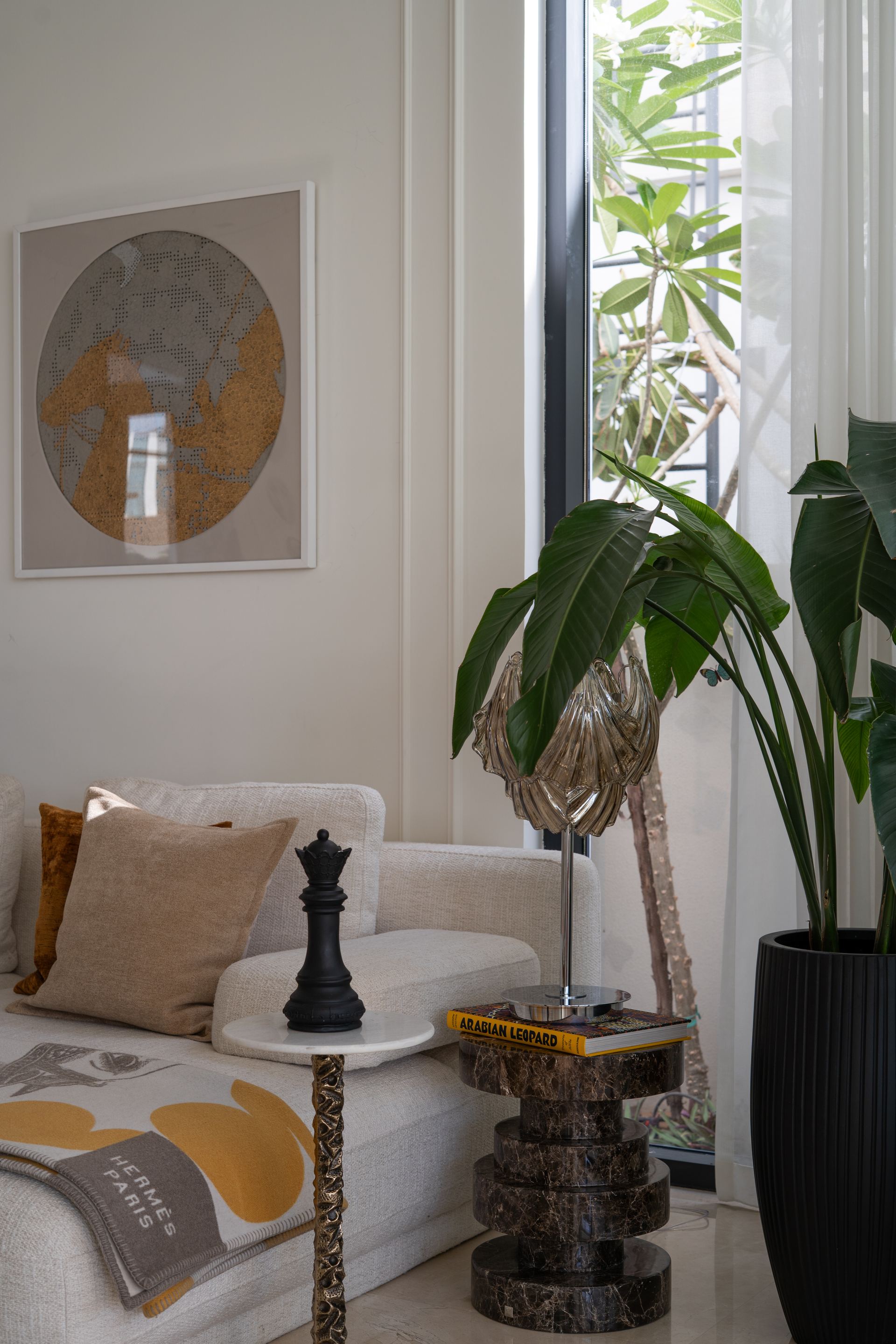Sculptural wood side table beside a linen sofa with mustard cushions
