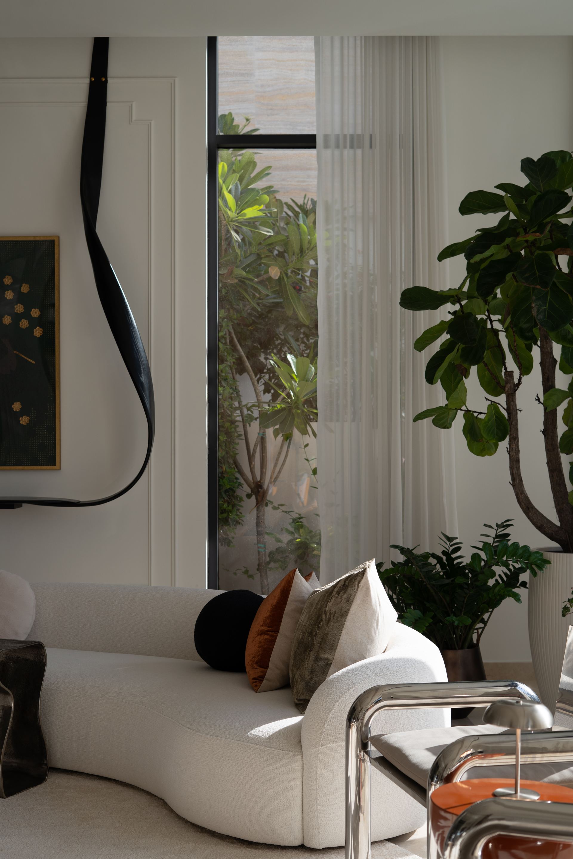 Sculptural black wall light beside a white daybed with mixed cushions