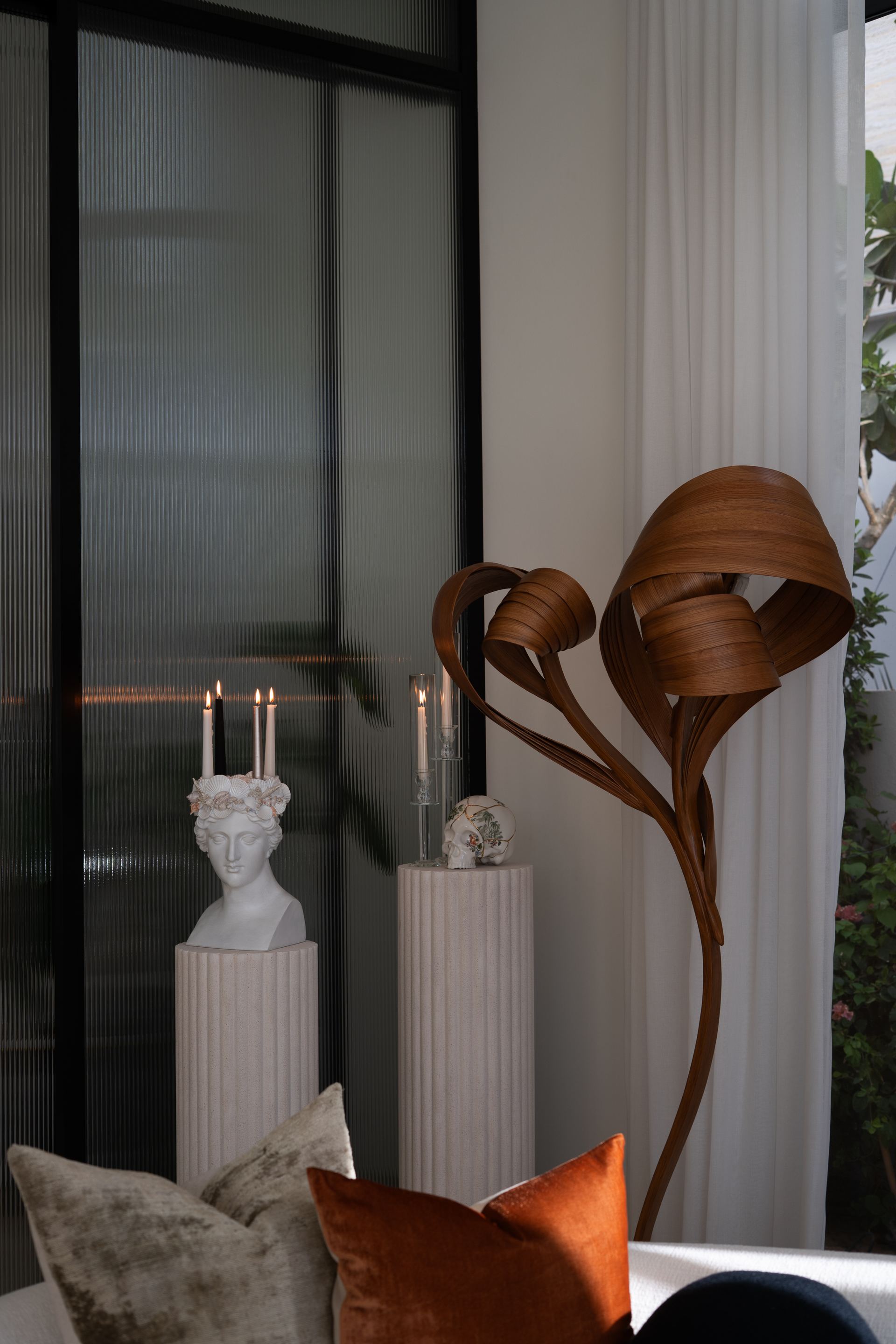 Marble bust candle holders beside a sculptural wood floor lamp