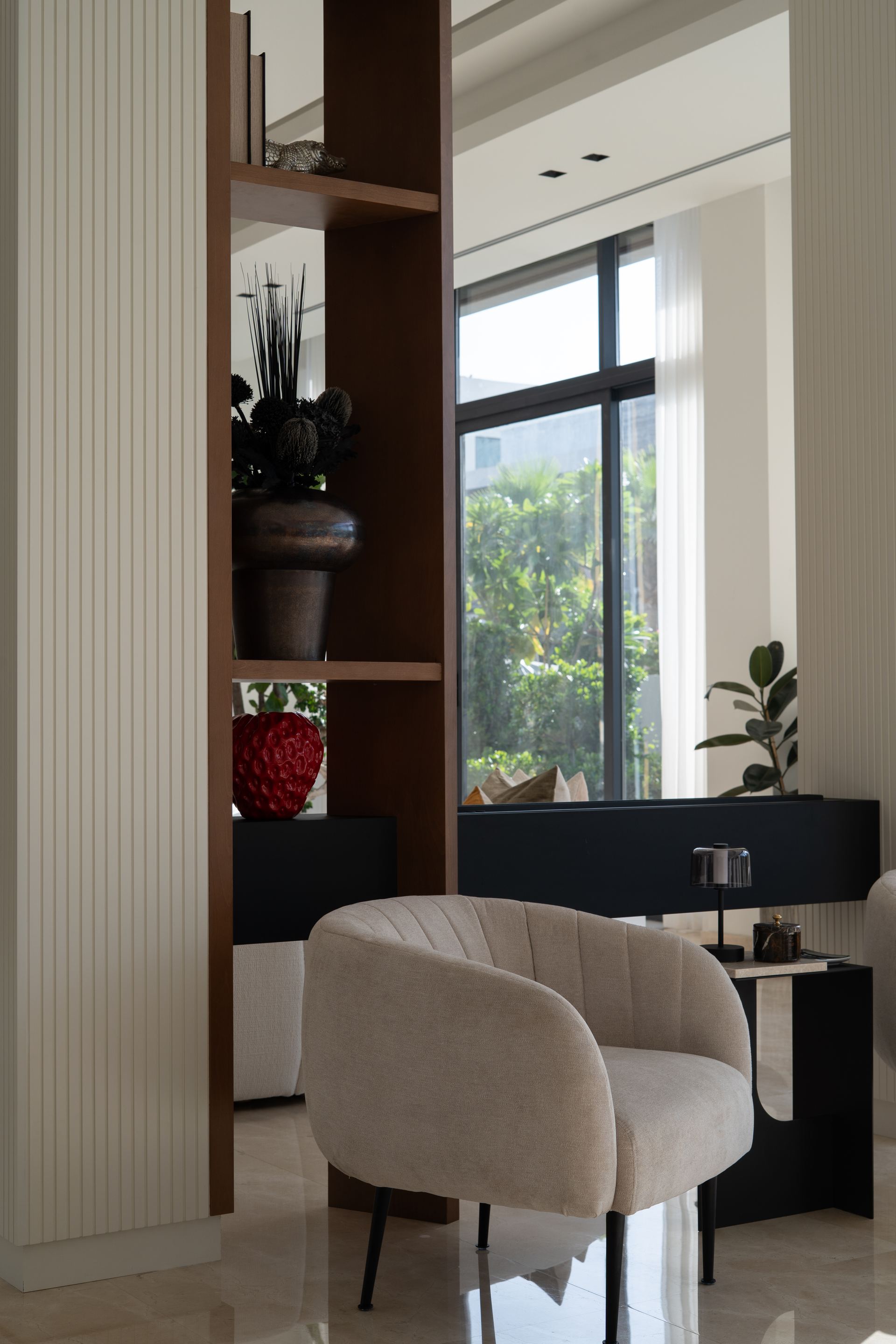 Rattan armchair beside a walnut display shelf and black console table
