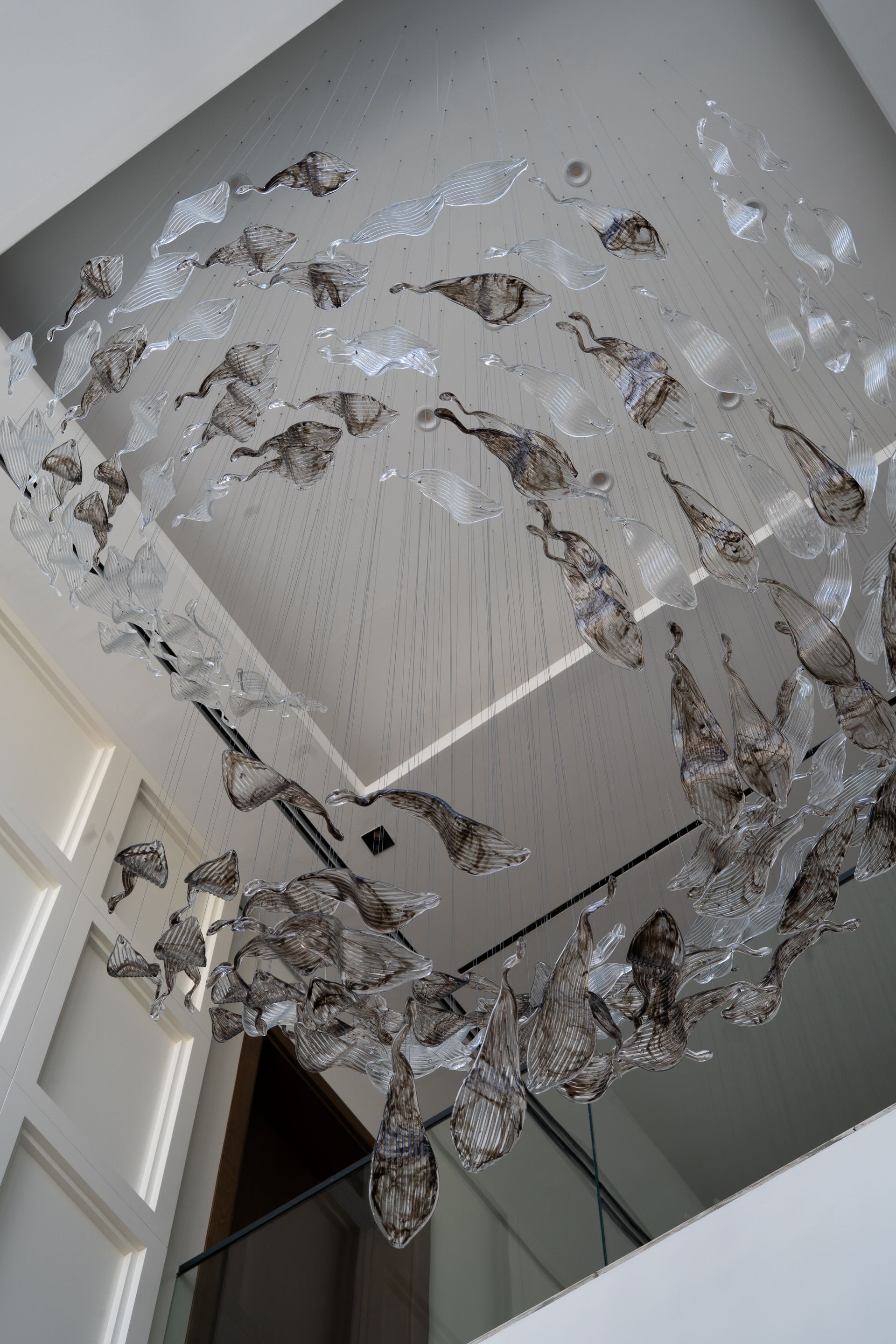 Sculptural glass chandelier suspended above a stairwell landing