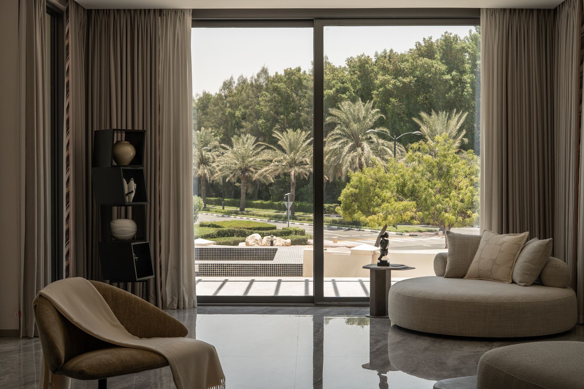 Curved bouclé daybed facing a garden view through floor-to-ceiling windows