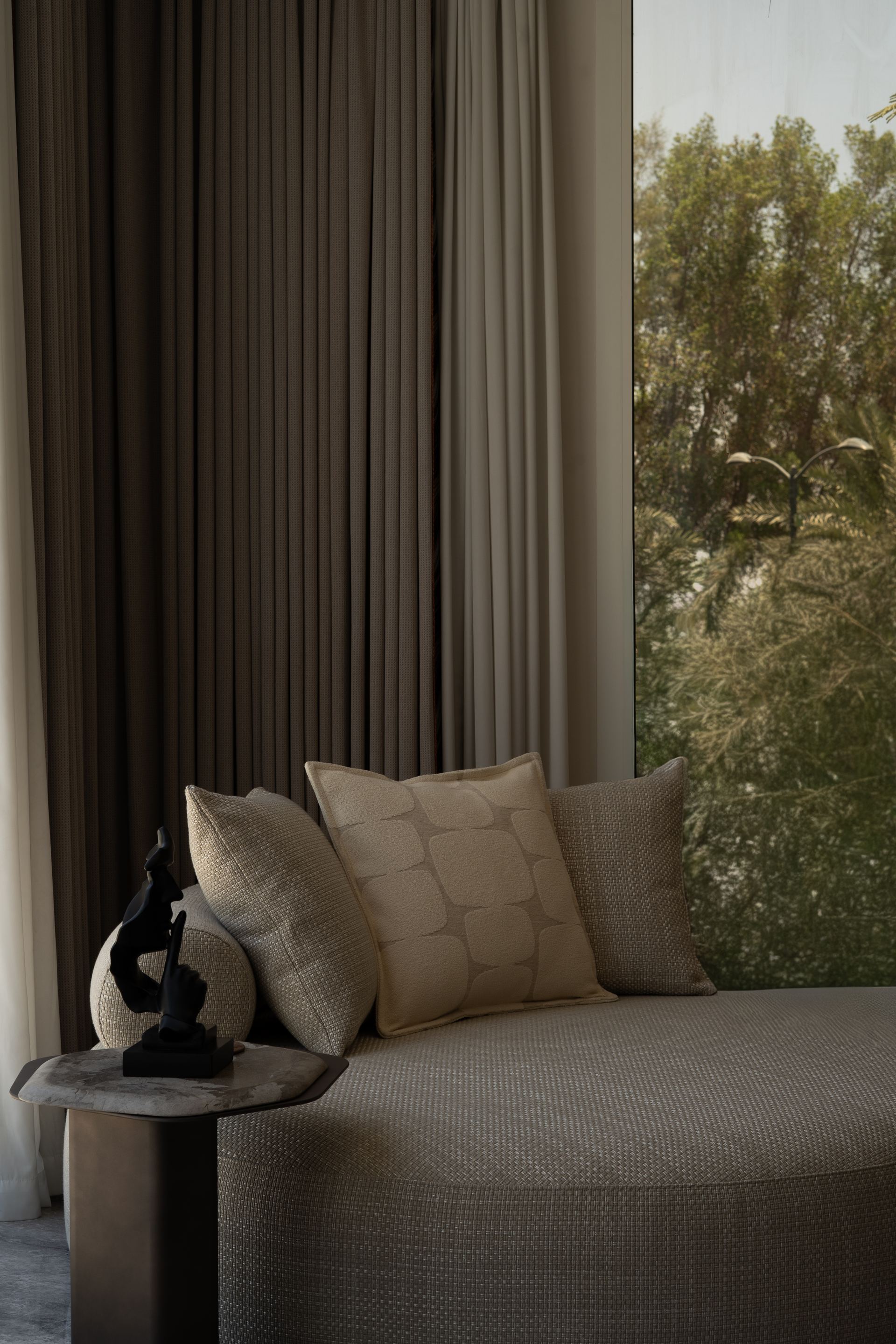Bouclé daybed with layered cushions beside floor-to-ceiling curtains