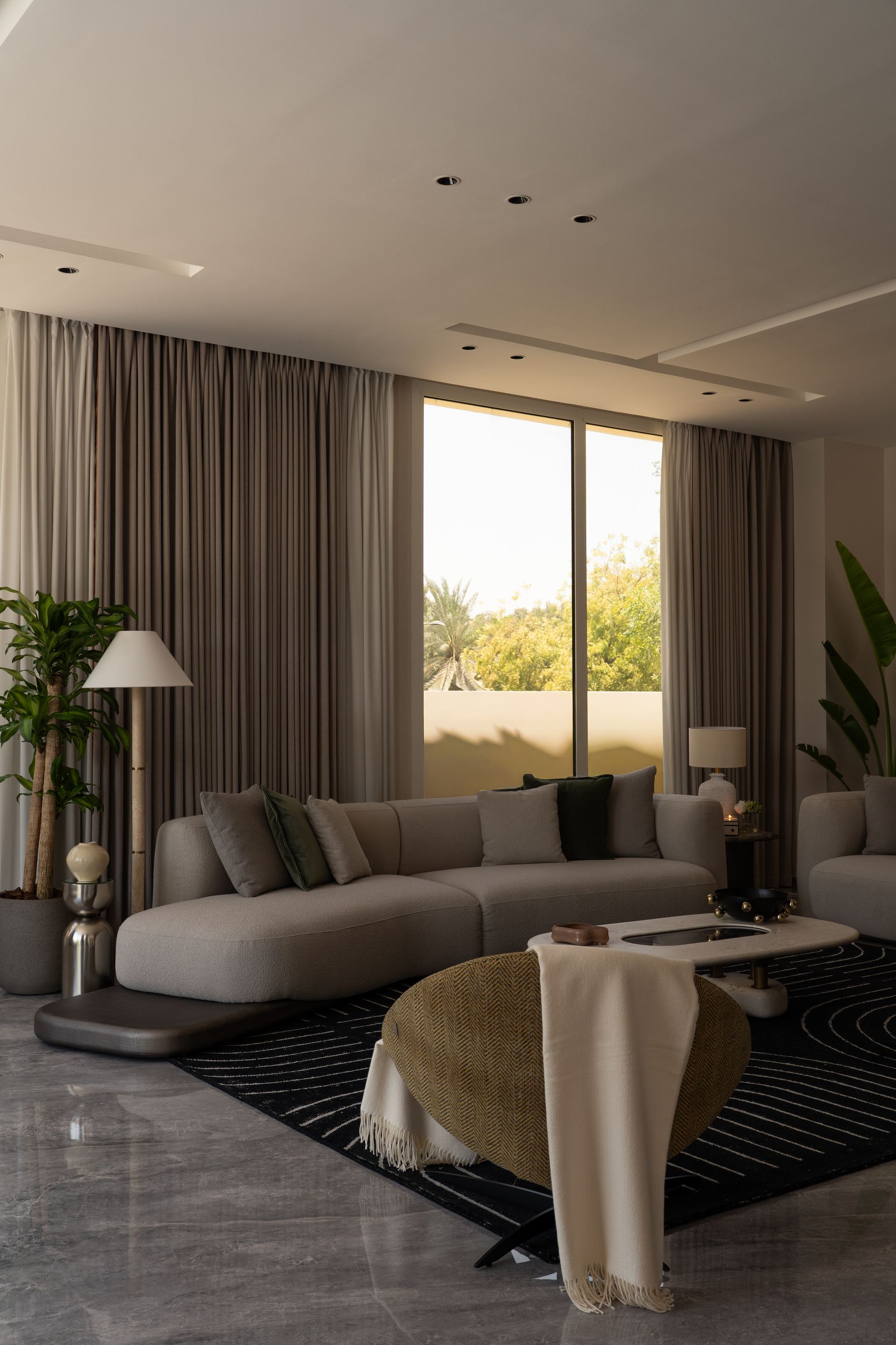 Grey bouclé sectional sofa with a black bowl on a round marble coffee table
