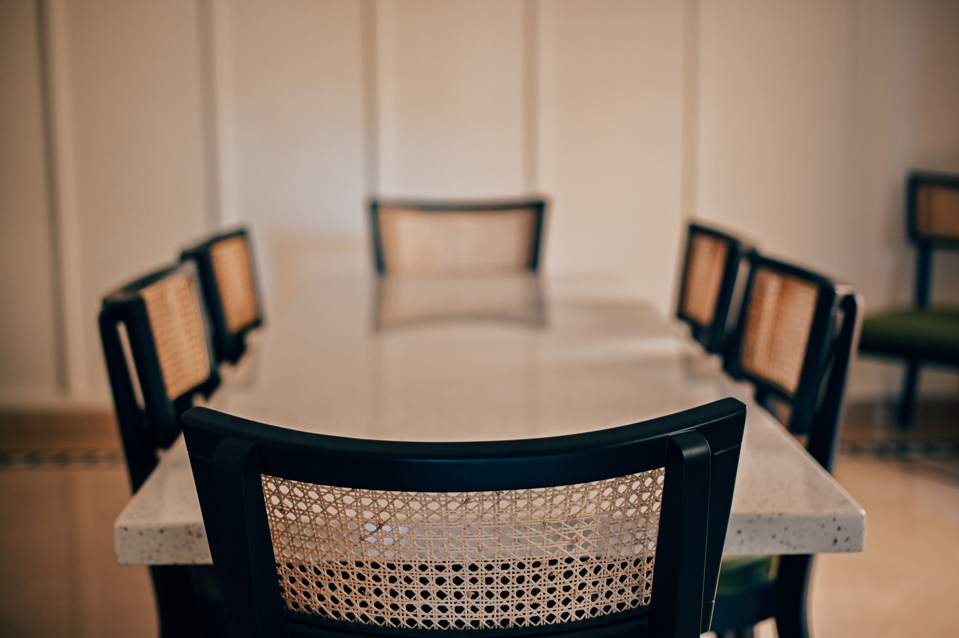 Cane-back dining chairs around a marble table framed by black doors