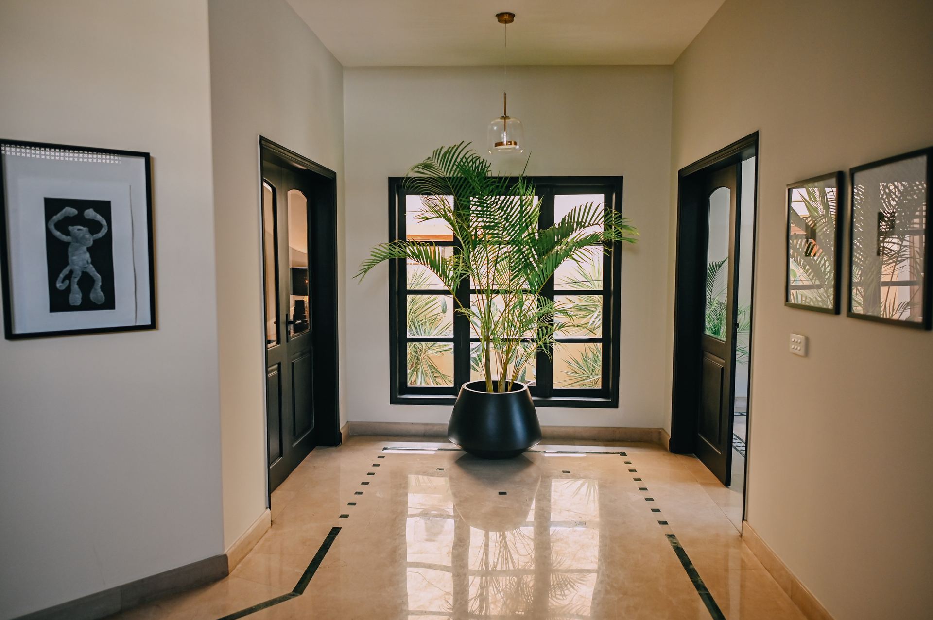 Potted areca palm in the entryway, framed by black doors and a patterned marble floor