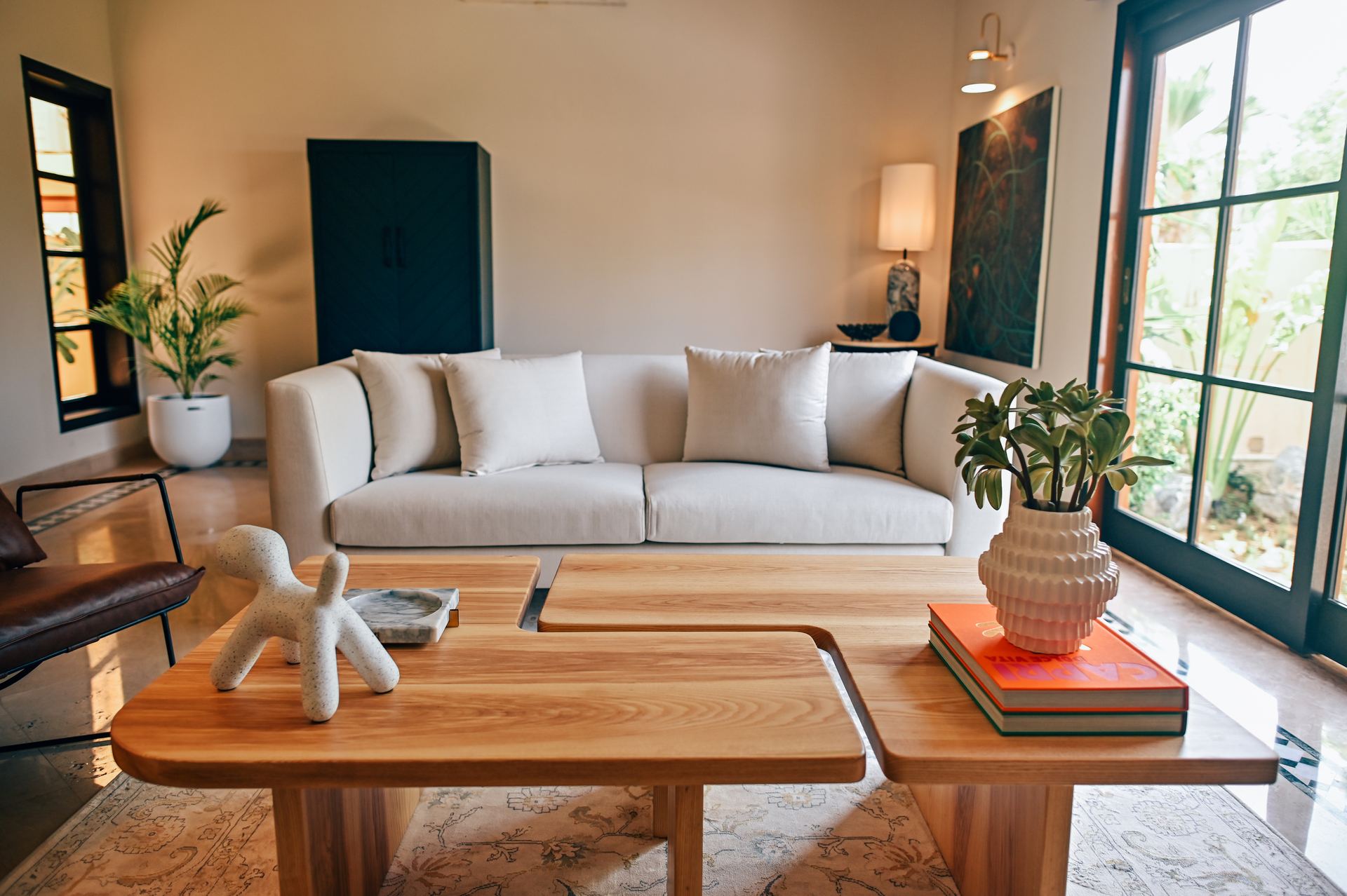 Cream sofa with layered pillows facing a wood coffee table styled with books