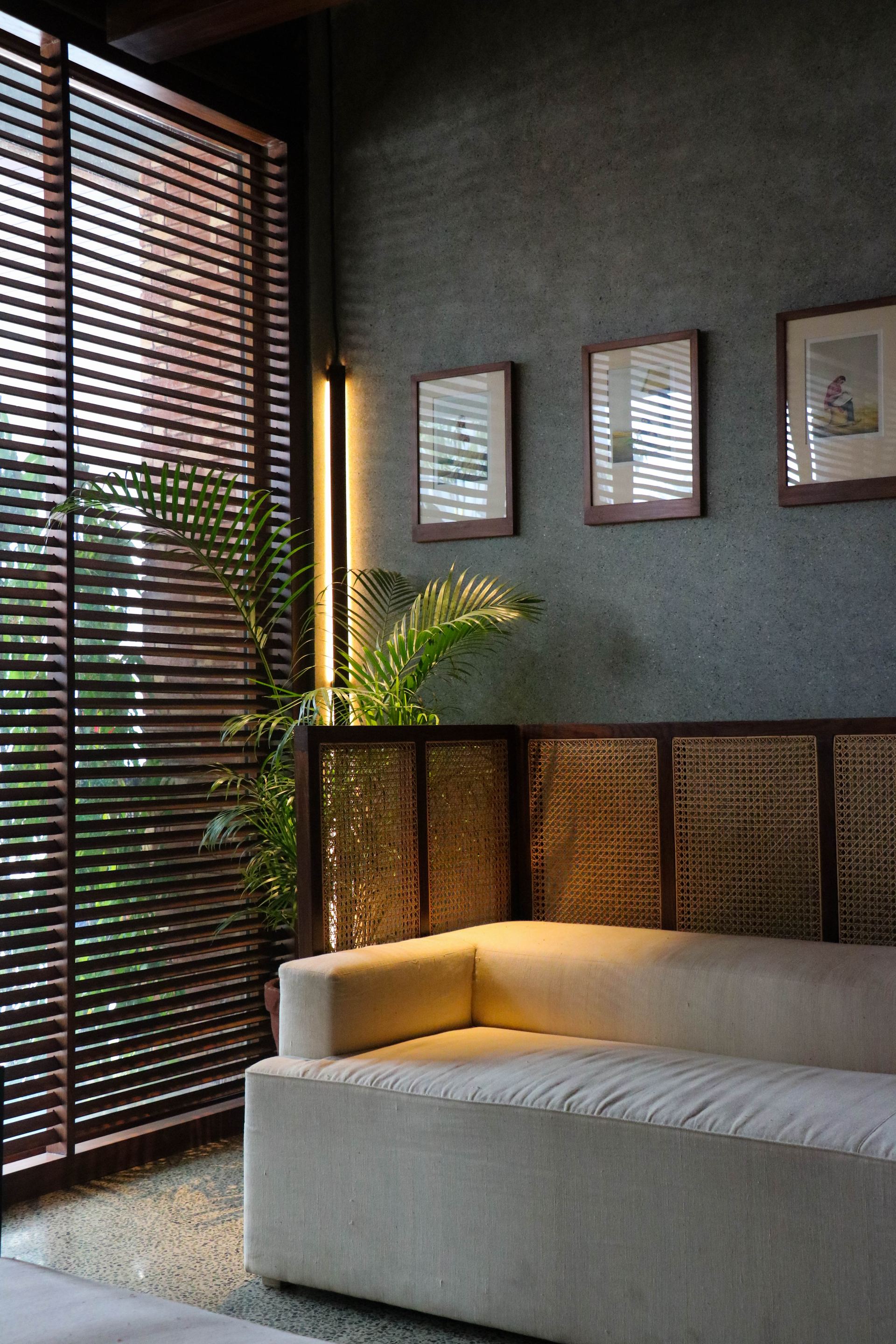 Cream lounge sofa beside a rattan-panelled screen and slatted timber blinds