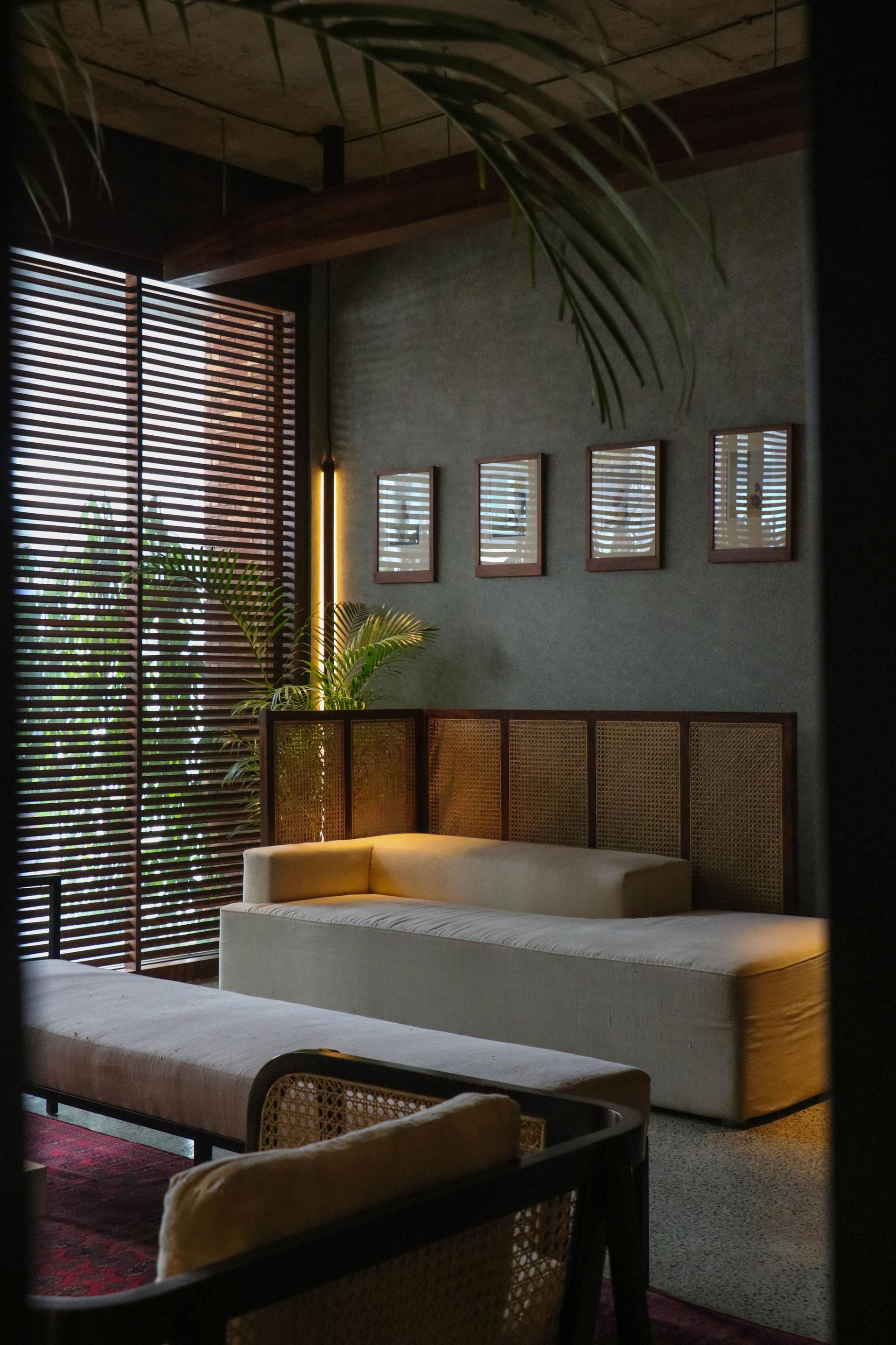 Cream banquette seating beside a rattan screen beneath framed archival photographs