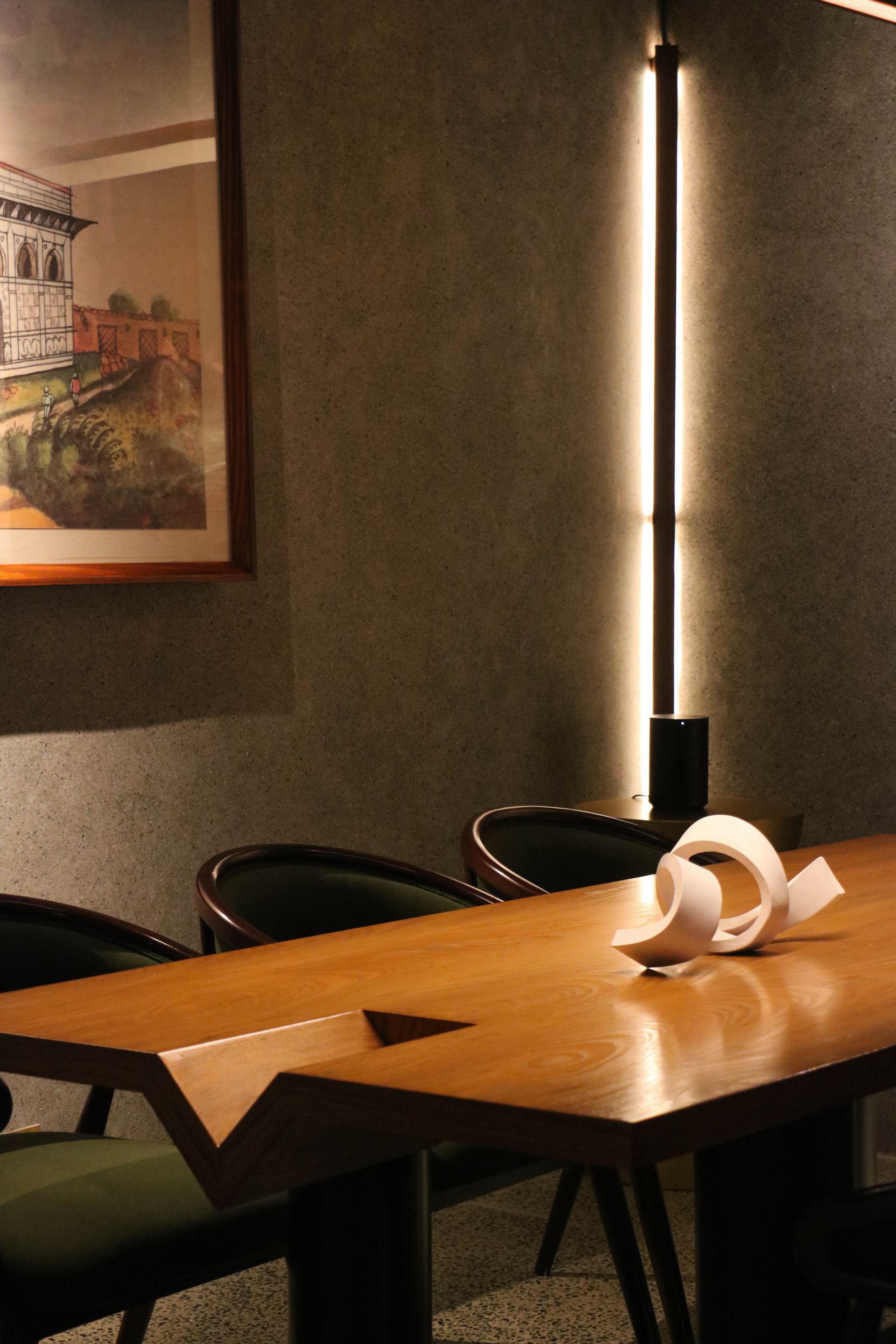 Paper sculpture centerpiece on a walnut dining table lit by a vertical strip light
