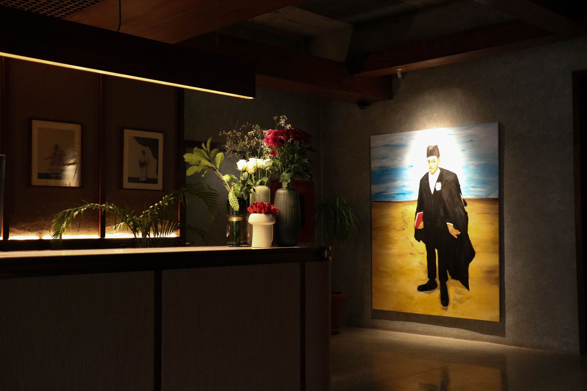 Framed portrait painting beside a bar counter styled with white and red florals